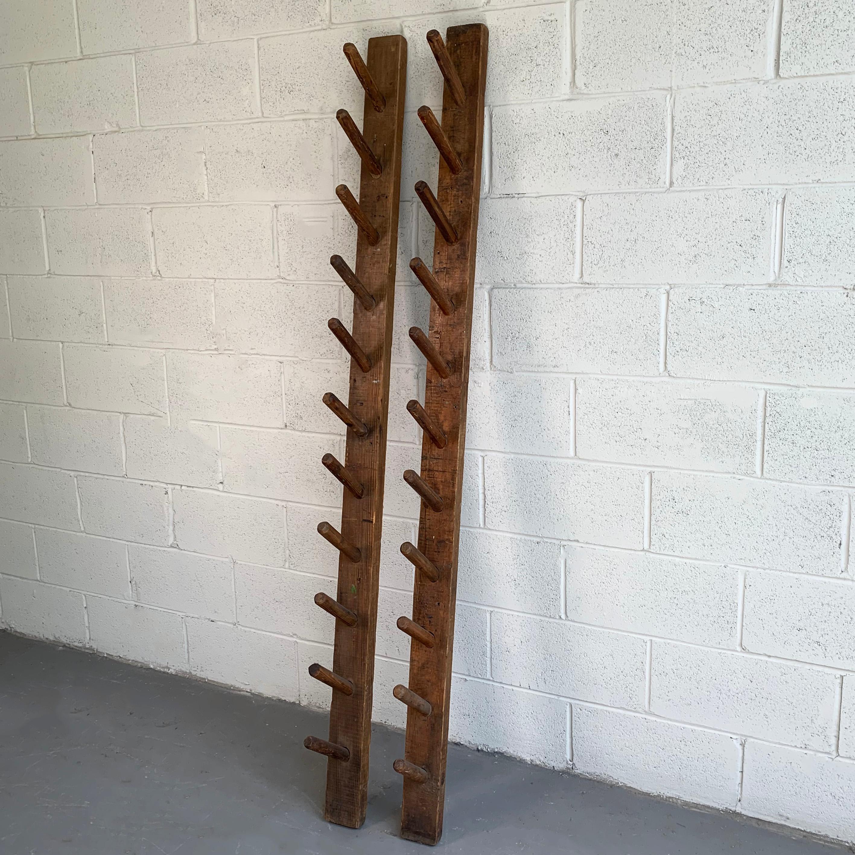 Pair of early 20th century, rustic, industrial, 6 foot, pine wall racks with slanted, dowel pegs.