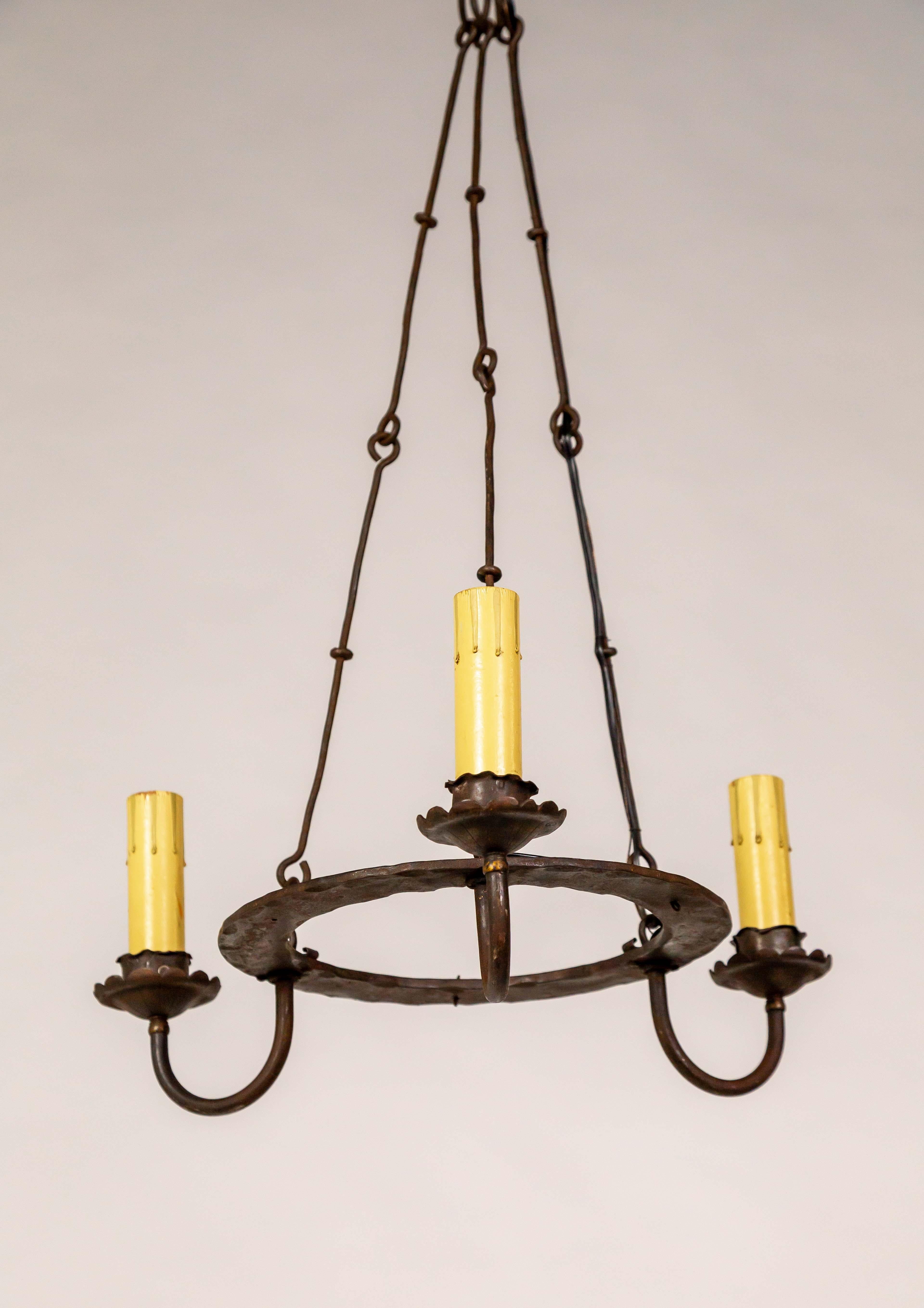 Lustre simple en anneau de fer de style Tudor, datant du début du 20e siècle. Il est d'une simplicité discrète, mais attire l'attention et est unique. Elle est en fer forgé avec un anneau central aplati qui laisse échapper trois lumières de style