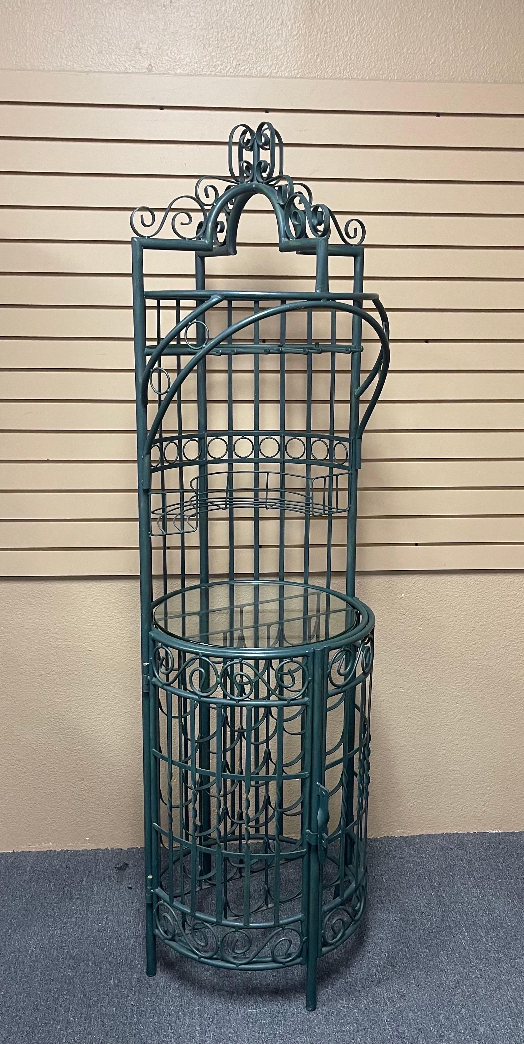 A very nice rustic iron wine rack / bar cabinet with double doors, storage and a glass shelf with a verdegris finish, circa 1970s. The piece is in rustic condition and holds 24 bottles of wine, 6 to 8 liquor bottles and barware. The cabinet has a