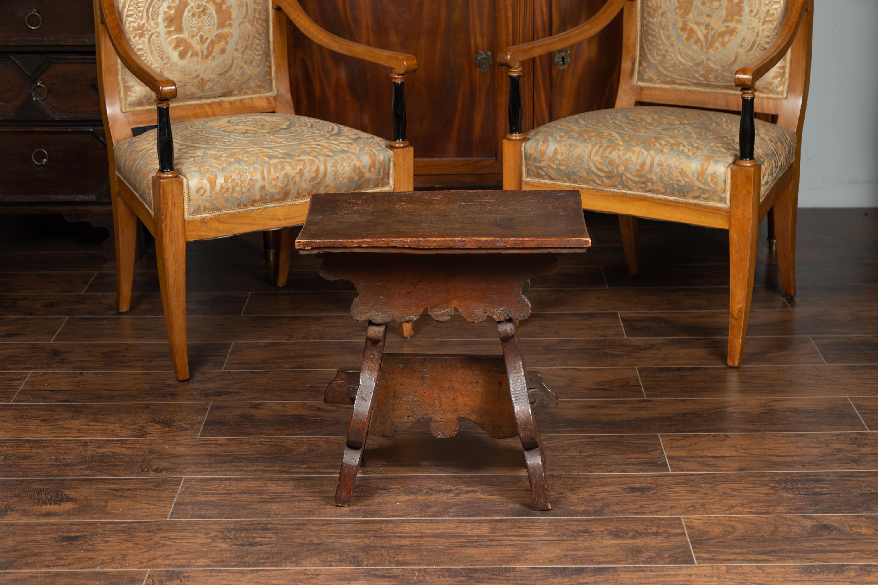 An Italian walnut stool from the early 19th century, with splaying trestle base and carved apron. Born in Italy during this early years of the 19th century, this charming walnut stool charms our eyes with its rustic appearance and great patina.