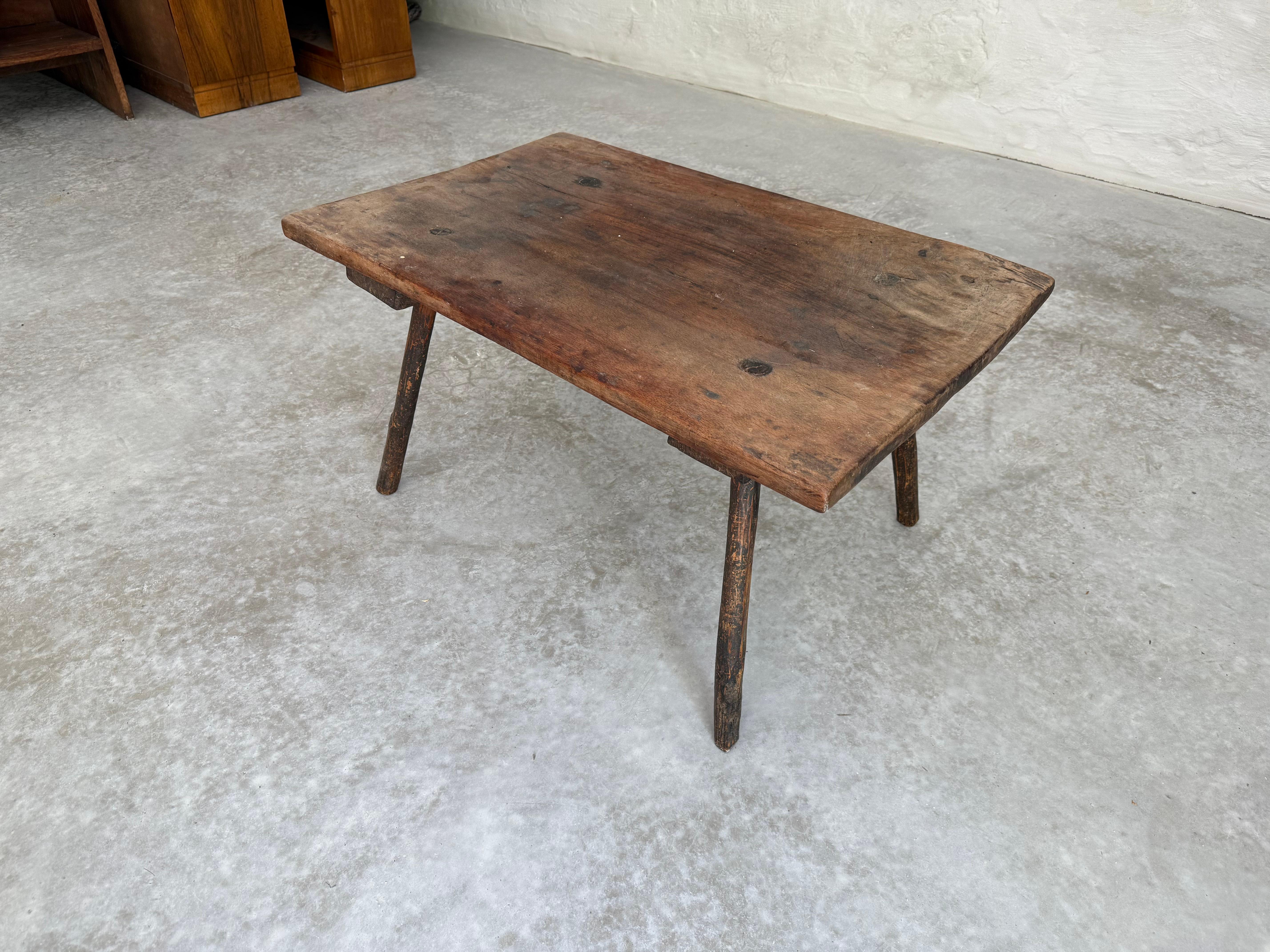 Table basse italienne en bois à plateau unique du XIXe siècle. Cette table ancienne d'Italie présente un plateau en bois à une seule planche, de forme rectangulaire avec des bords lissés. Il repose sur quatre pieds qui s'inclinent vers l'extérieur.