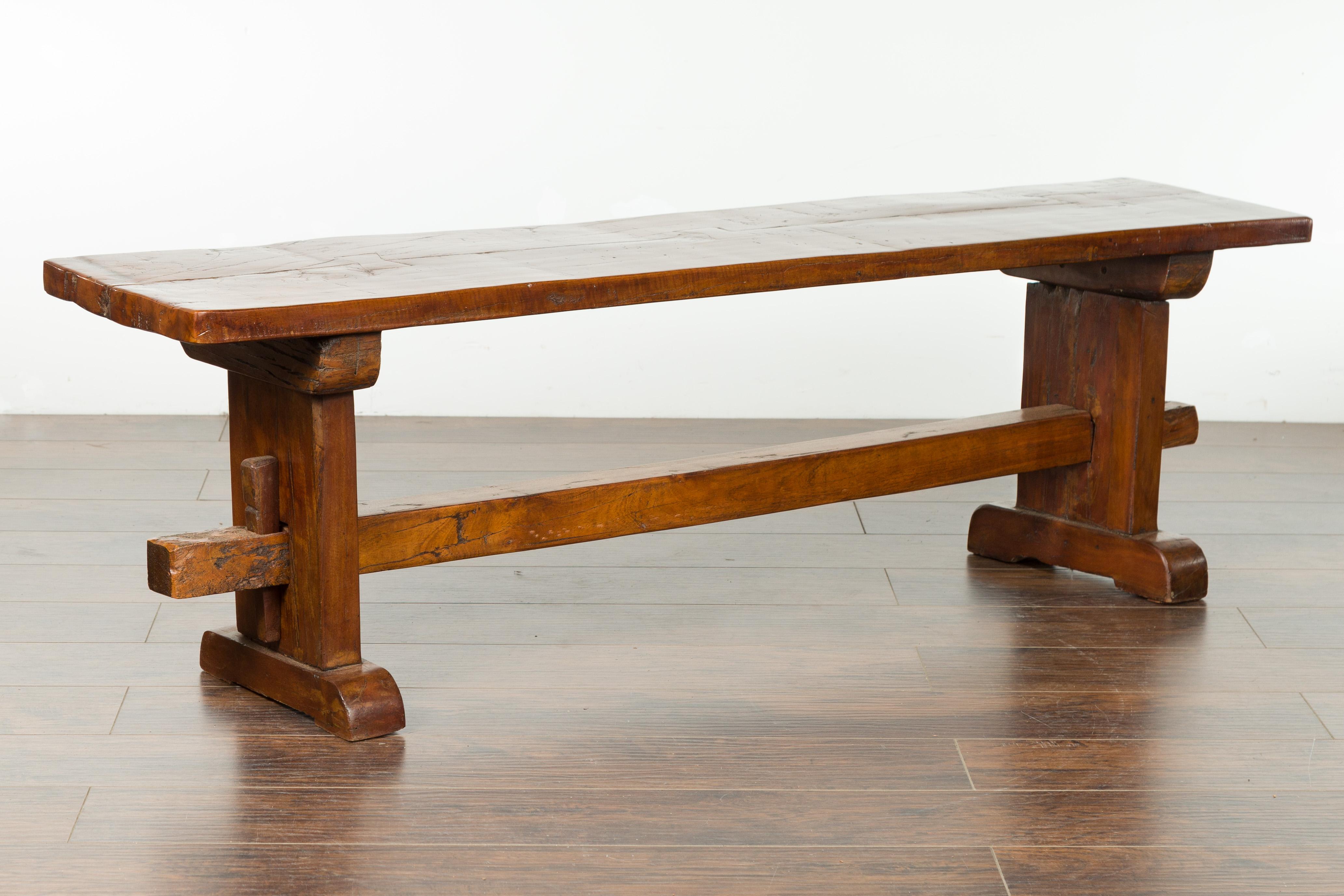 An Italian walnut bench from the early 19th century, with trestle base. Created in Italy during the first quarter of the 19th century, this walnut bench charms us with its rustic presence and nicely weathered patina. A rectangular top sits above a