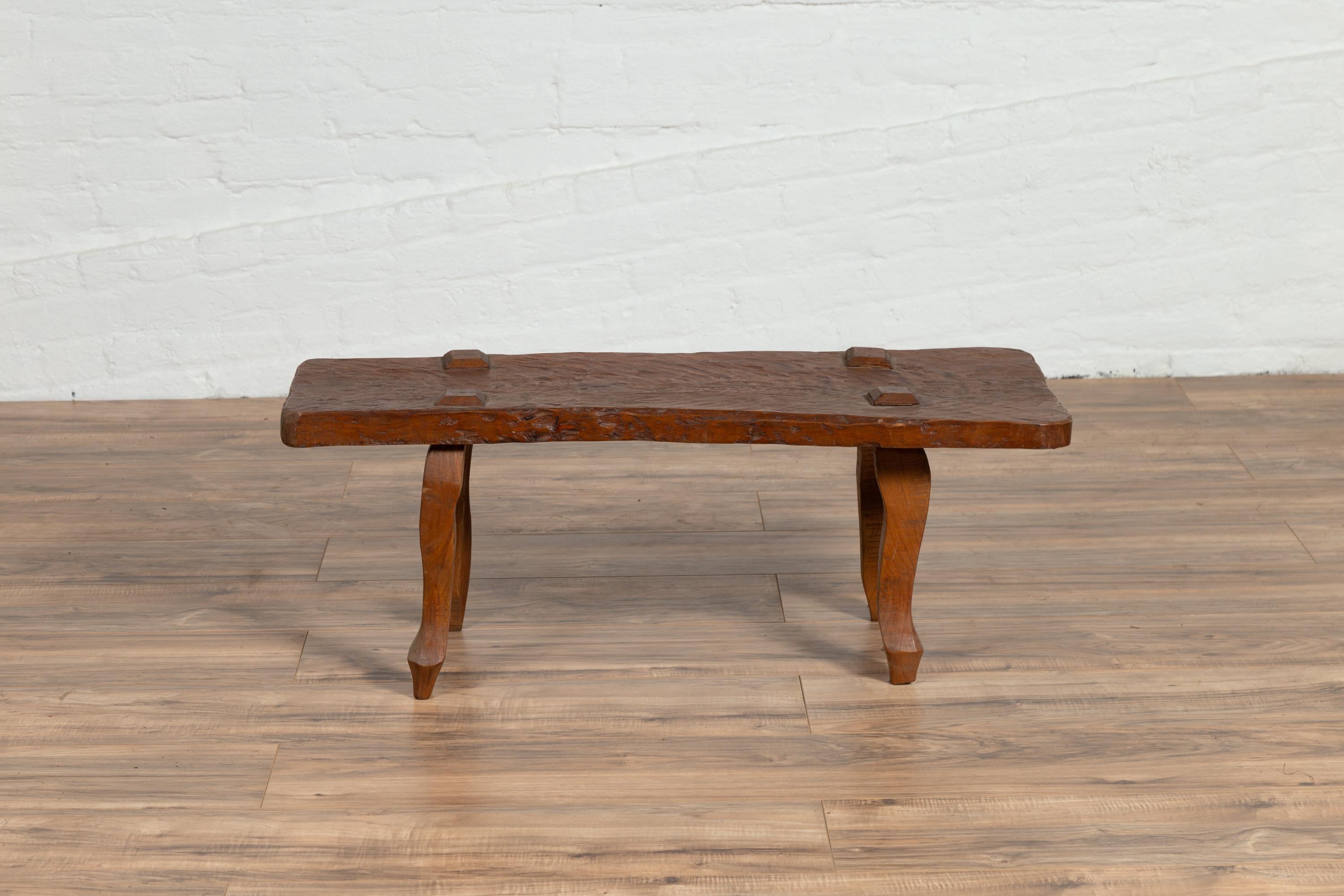 A Javanese freeform low bench made of antique reclaimed teak wood with textured appearance. Born on the island of Java in the early years of the 20th century, this rustic bench features a nicely textured top with protruding raised joints, sitting