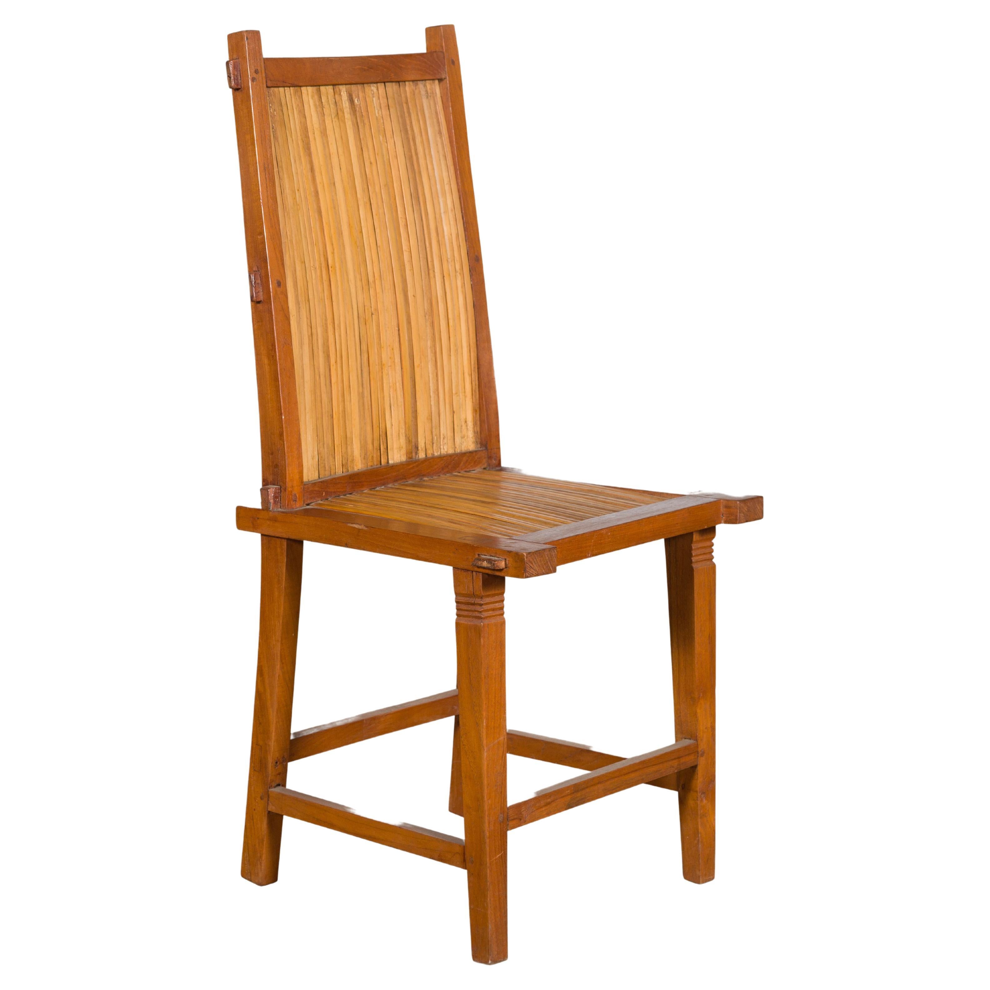 A rustic vintage Javanese side chair from the mid 20th century with slatted bamboo back and seat. Created on the island of Java during the Midcentury period, this side chair features a slanted back made of a wooden frame securing slatted bamboo. The