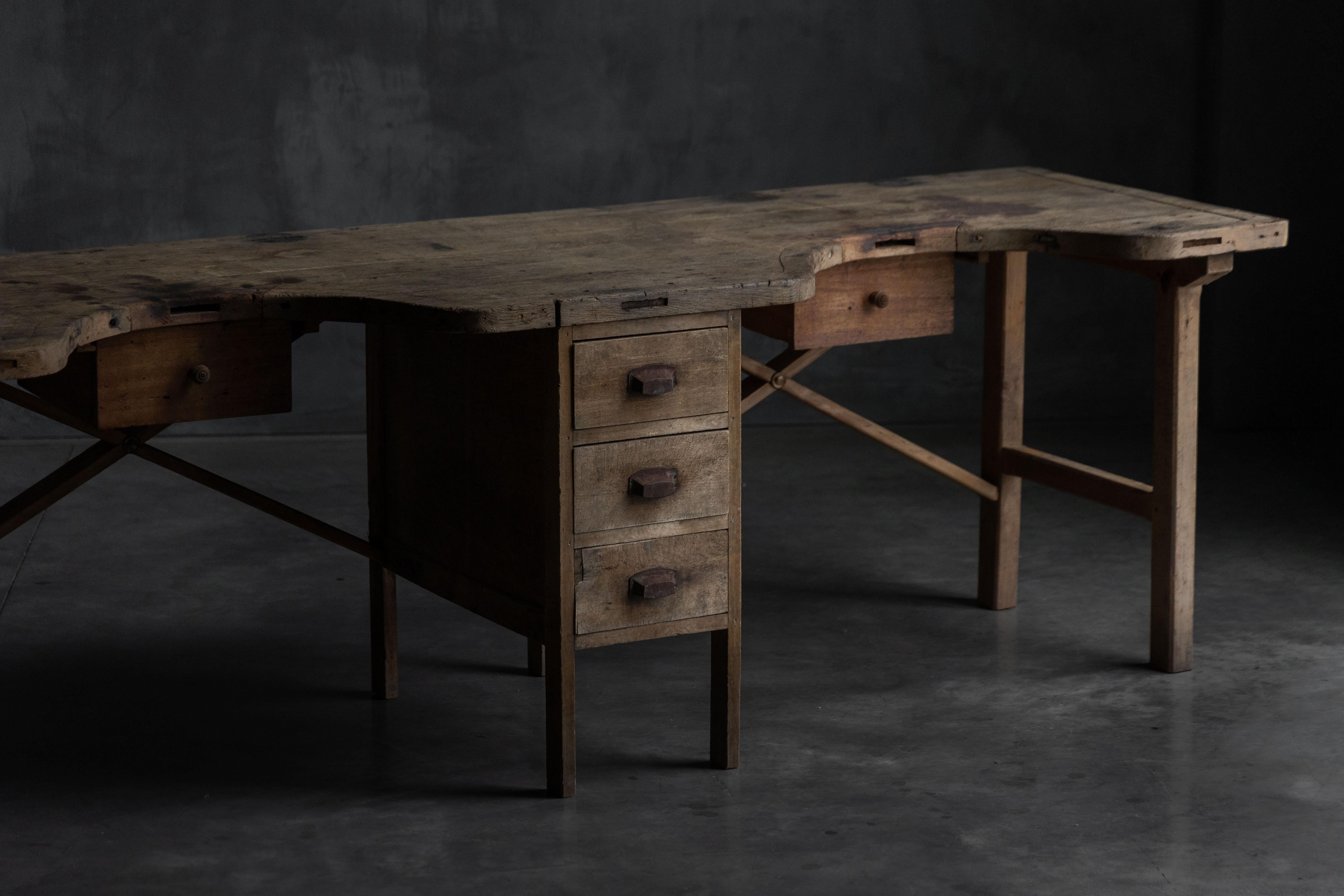 Cet ancien établi de bijoutier est une rare table d'atelier à double face qui témoigne de générations d'artisans qualifiés. Avec une surface robuste et asymétrique en bois massif portant les marques d'années d'utilisation, il offre à la fois