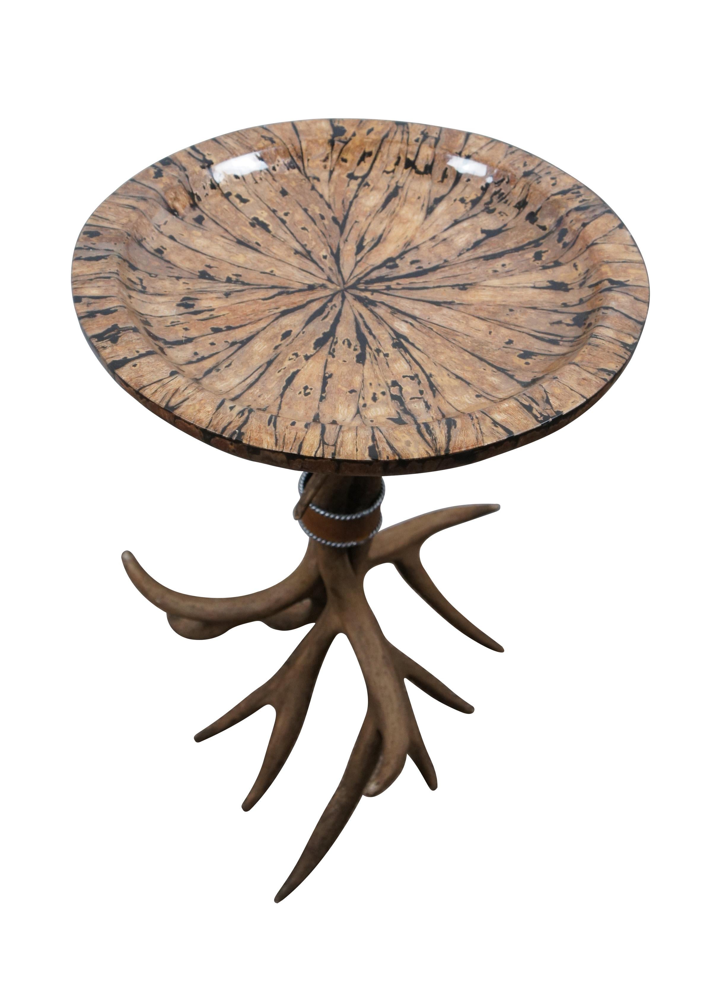 Late 20th century rustic country farmhouse / log cabin / lodge / hunt theme side / accent / cocktail table. Round top of lacquered inlaid wood with a concave surface, supported on three faux antlers bound with a leather and silver tone band.