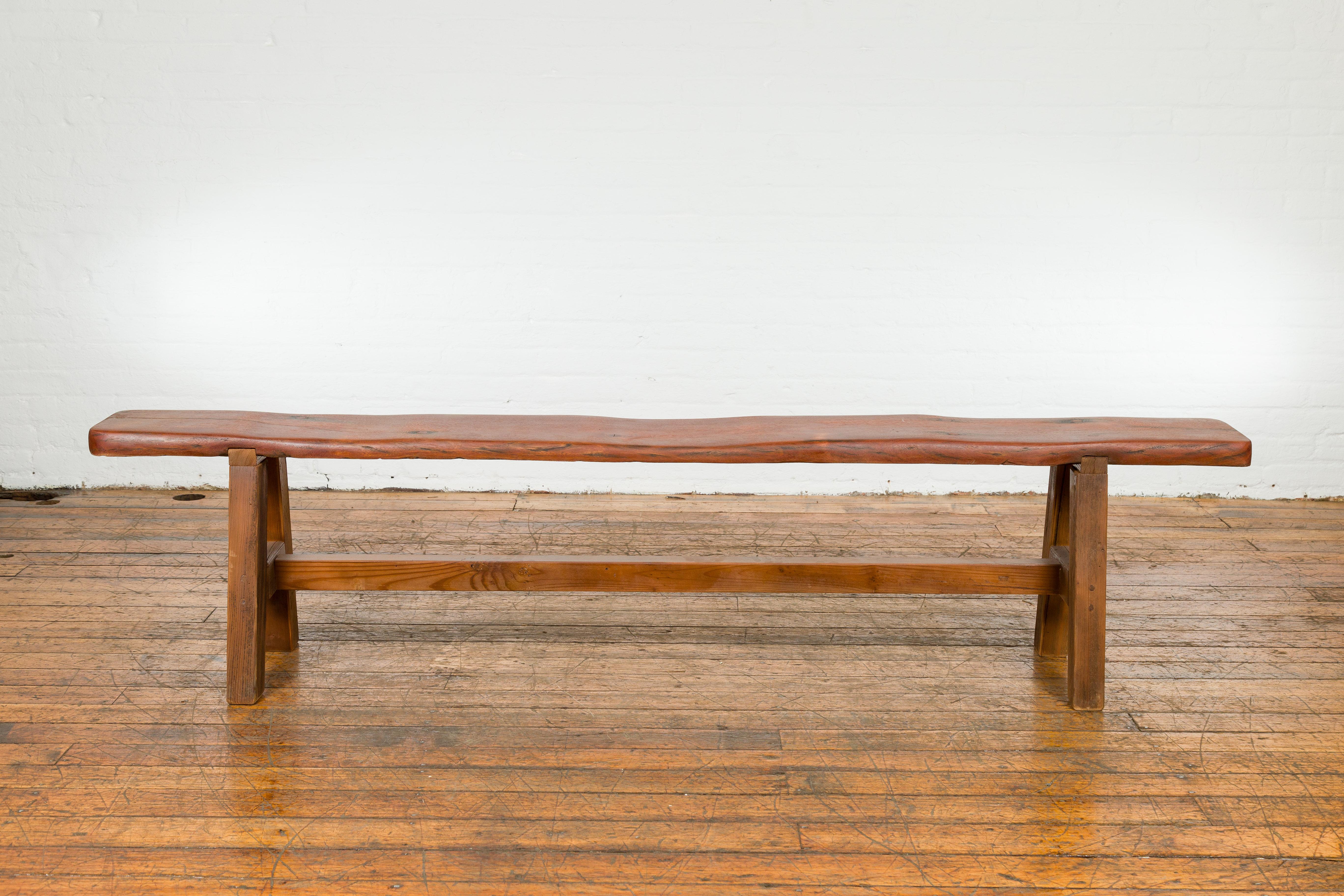 An antique long A-Frame wooden bench with rustic appearance and H-Form stretcher. Immerse yourself in the rustic charm of this antique long A-Frame wooden bench, a piece that radiates with history and robust simplicity. Its extended length and