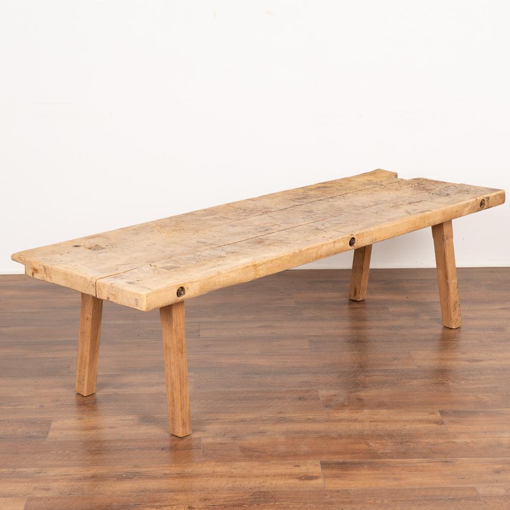 Rustic 6' long slab wood coffee table made from three heavy planks and loaded with vintage character.
The thick top is covered in scrapes, deep gouges, stains and markings acquired with over 100 years of use as a work table.
Iron bolts in the side