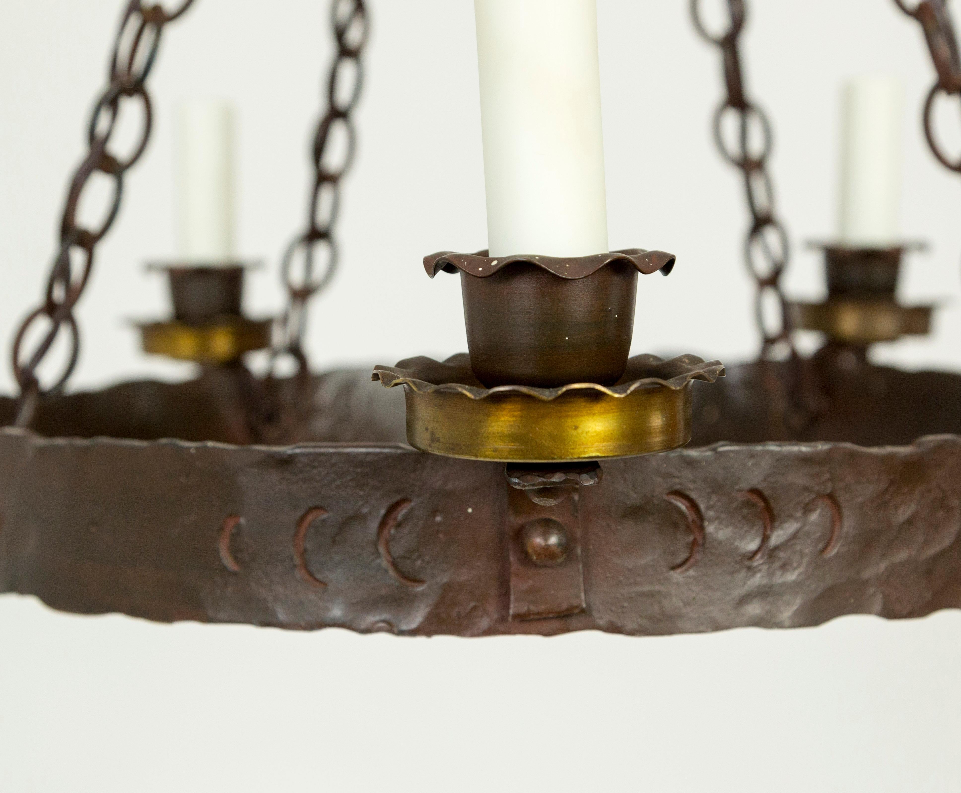 Hand wrought iron, Medieval Revival chandelier with hammered texture, brass candle cups, and poly-beeswax candle covers. American, 1910. Newly wired. 22