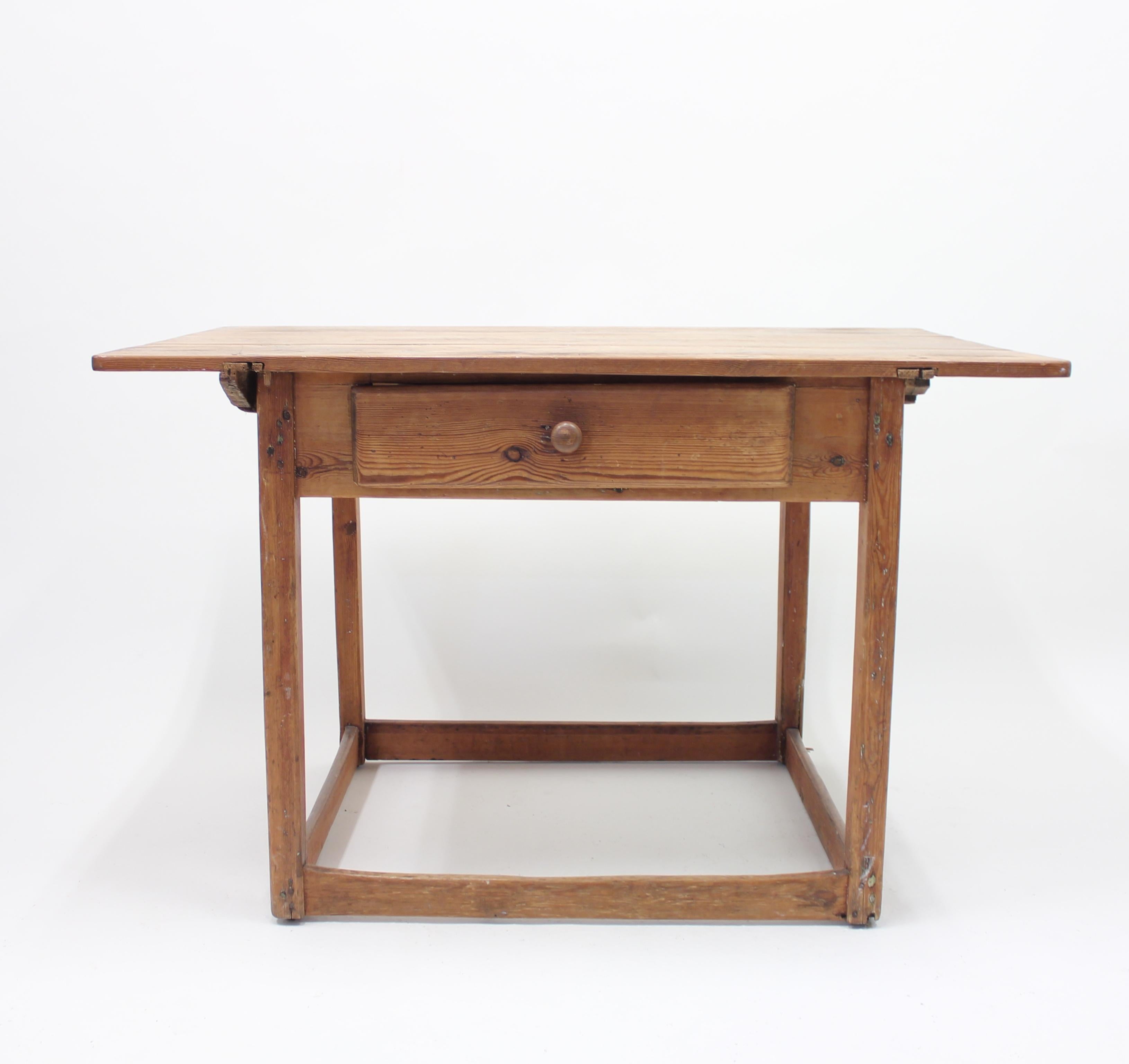 Antique Swedish rustic pine table that originates from the town Härnösand in the northern parts of Sweden. Made circa 1850 or slightly earlier. It features a removable three plank tabletop and a drawer on one side. The model will be perfect as a