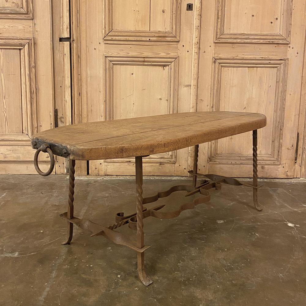 Rustic midcentury oak and wrought iron coffee table was literally designed to last for centuries! Using thick, solid planks of old growth oak, the artisans fashioned a traffic friendly shape with no sharp corners, then fitted the ends with forged
