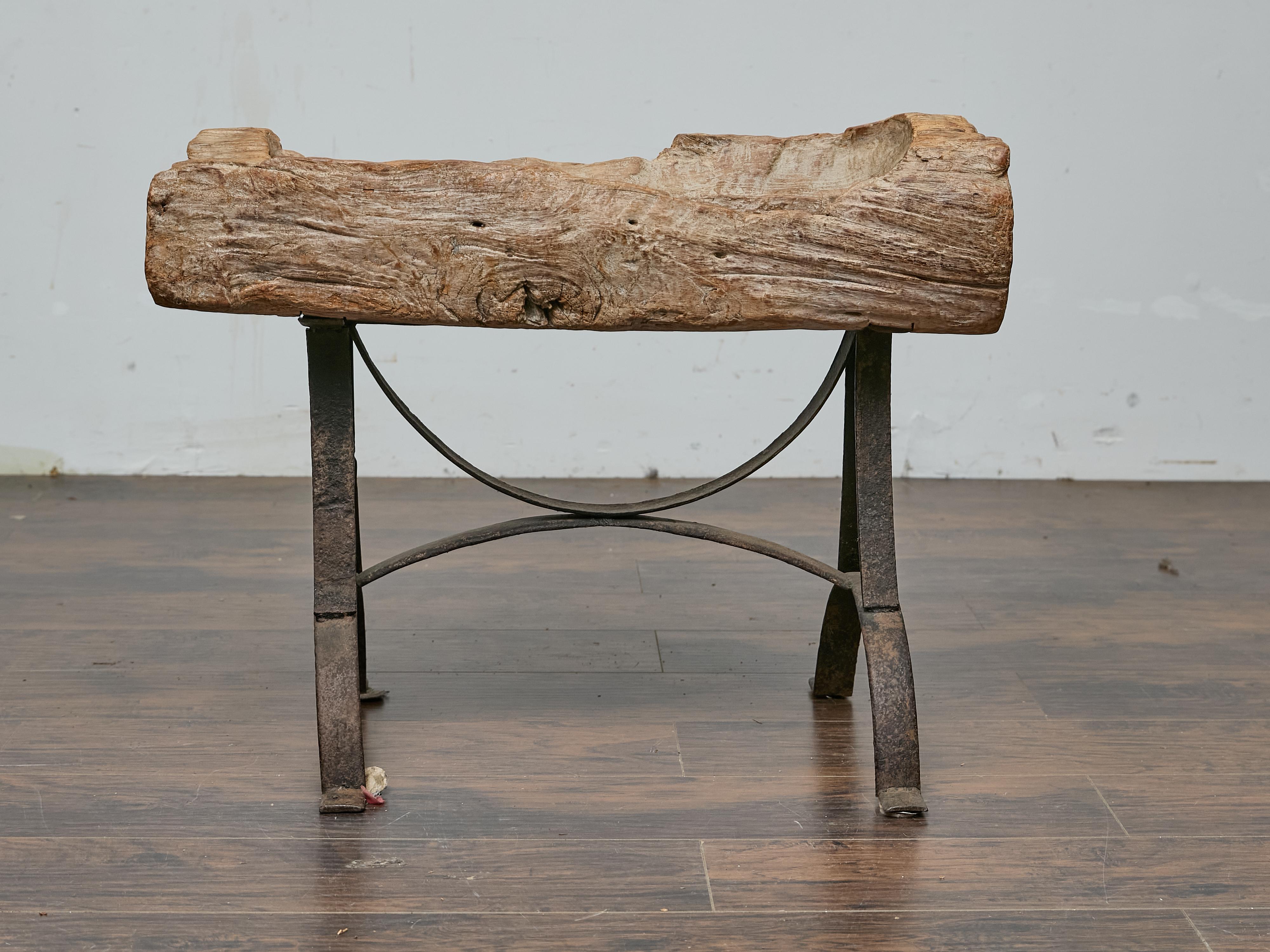 Pièce frappante du design rustique américain, cette auge du milieu du XXe siècle réutilise la beauté brute du bois vieilli avec une base en fer robuste, mêlant textures organiques et force industrielle. L'auge en bois sculptée à la main conserve son