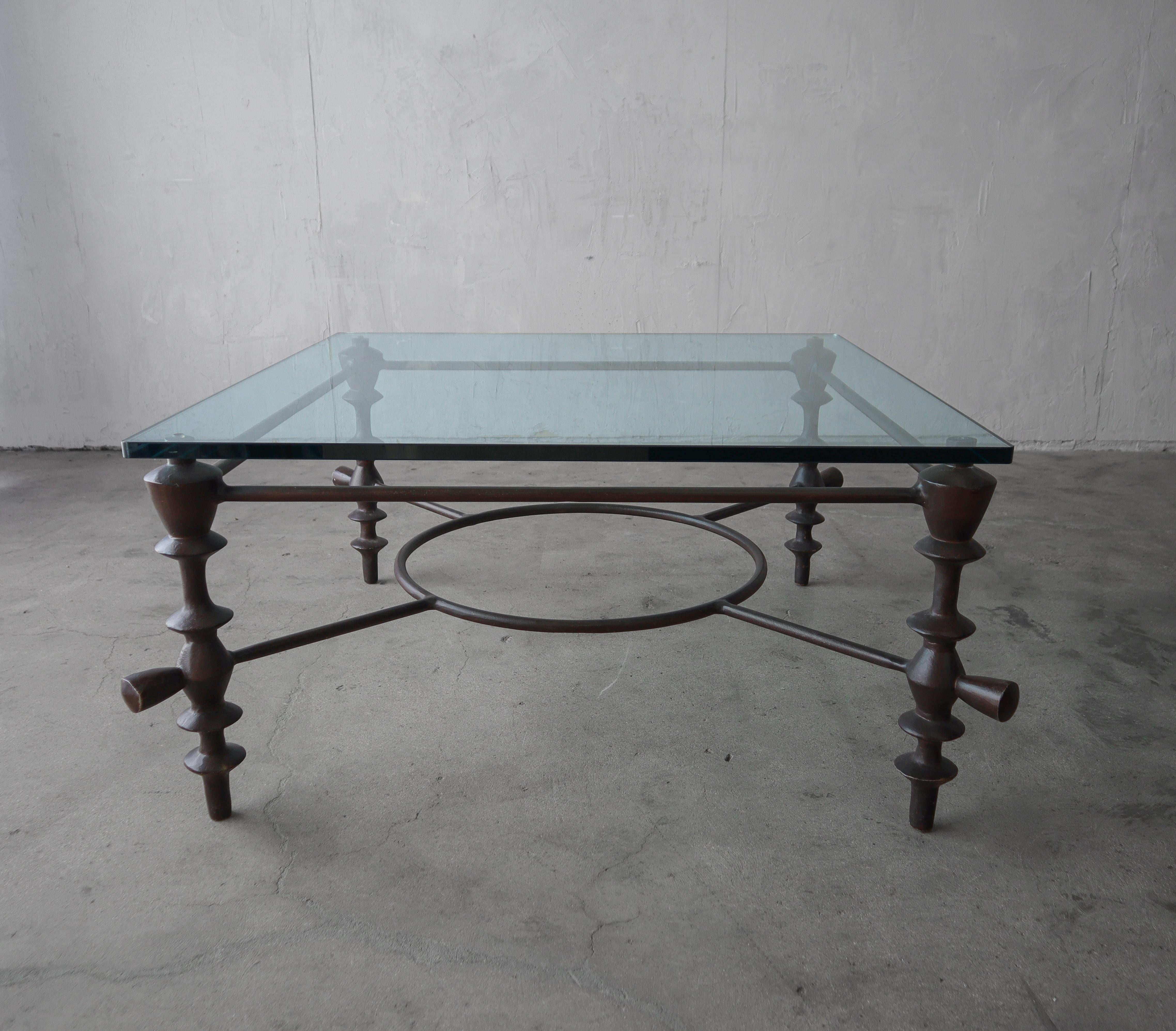 Substantial and gorgeous sculptural coffee table in the style of Diego Giacometti. Table base is cast aluminum with a bronze finish and beautiful glass top.
 
 A very clean, minimal design, perfect for many design aesthetics.

Balance of table is in