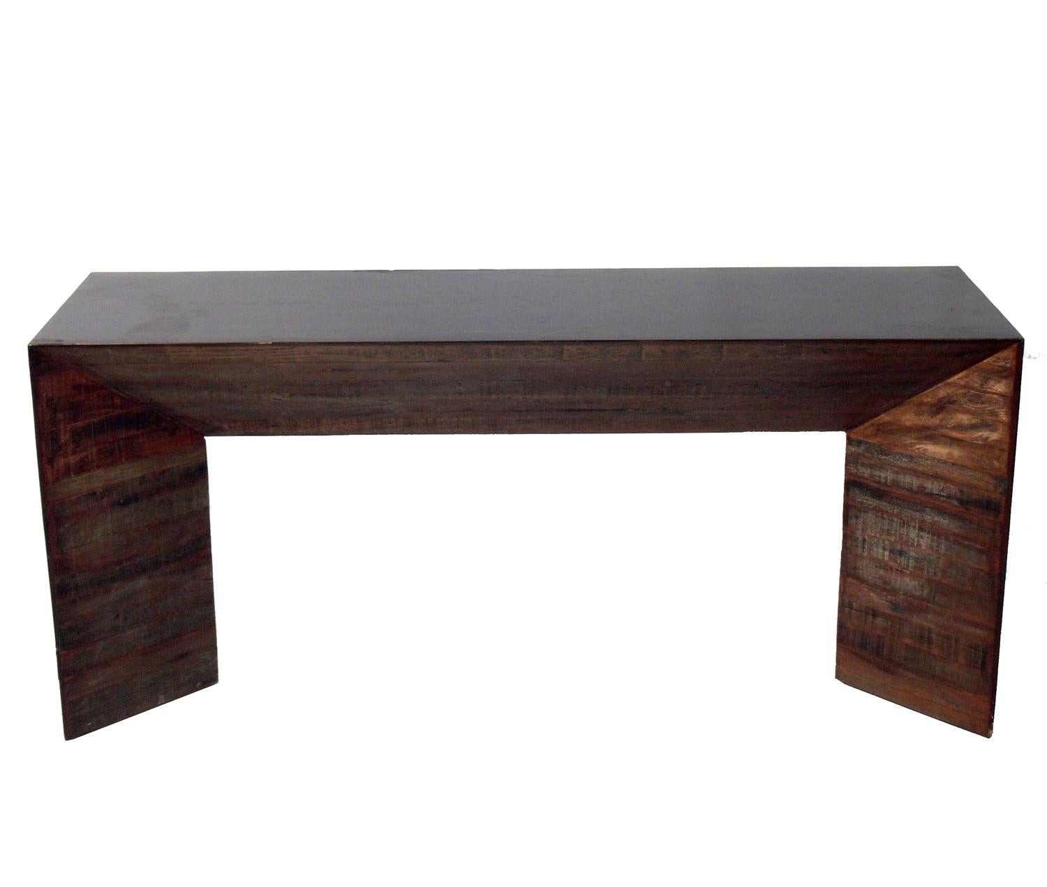 Rustic modern console table, American, 20th century. This piece is a versatile size and can be used as a console or sofa table, desk, bar, or media center for your TV. It is constructed of stacked rustic wood with a sleek top and sides.