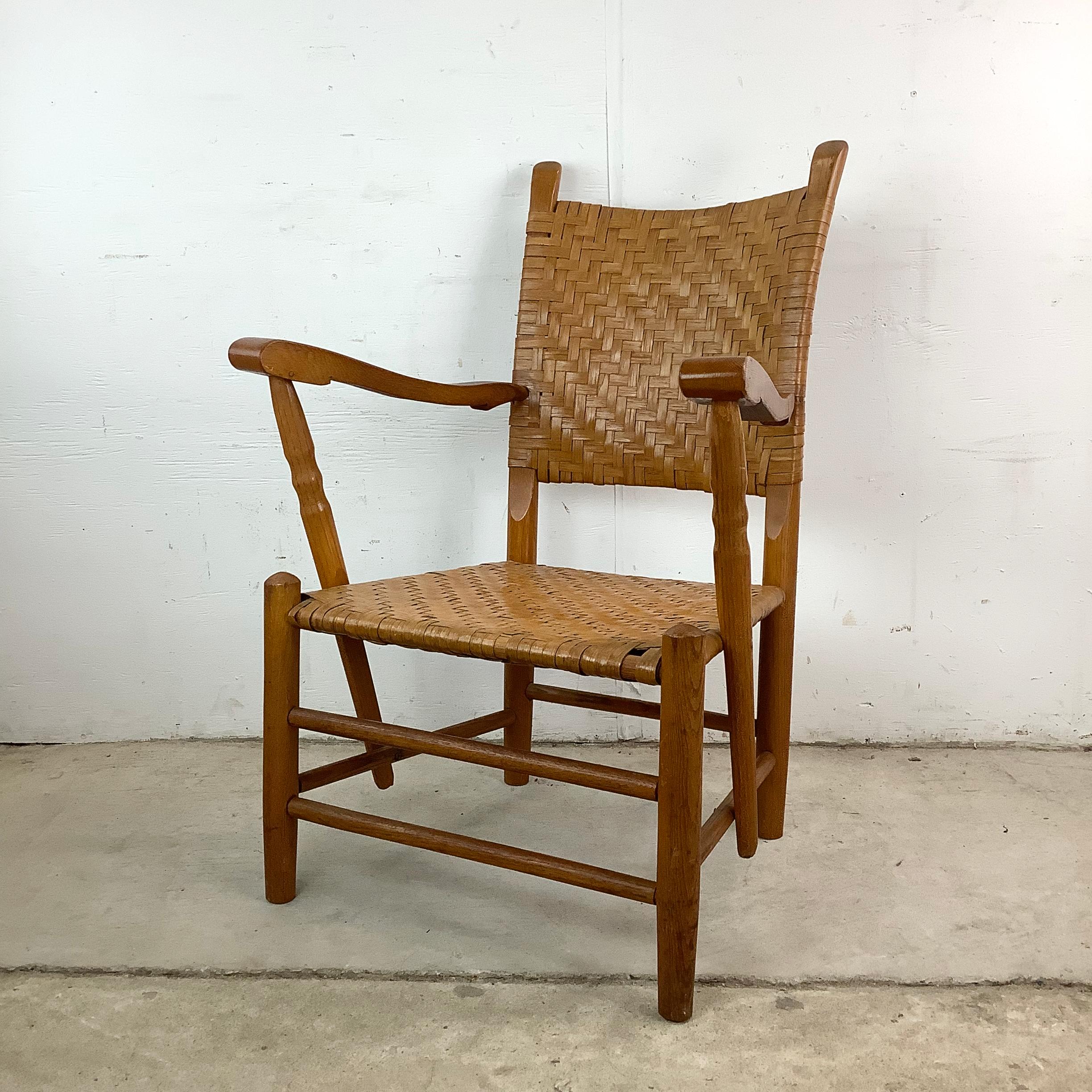 This vintage armchair showcases a solid oak frame paired with a woven rattan seat and backrest, evoking the rustic charm of traditional Hickory-style furnishings. The sculptural form is both functional and visually appealing.

The gently curved arms