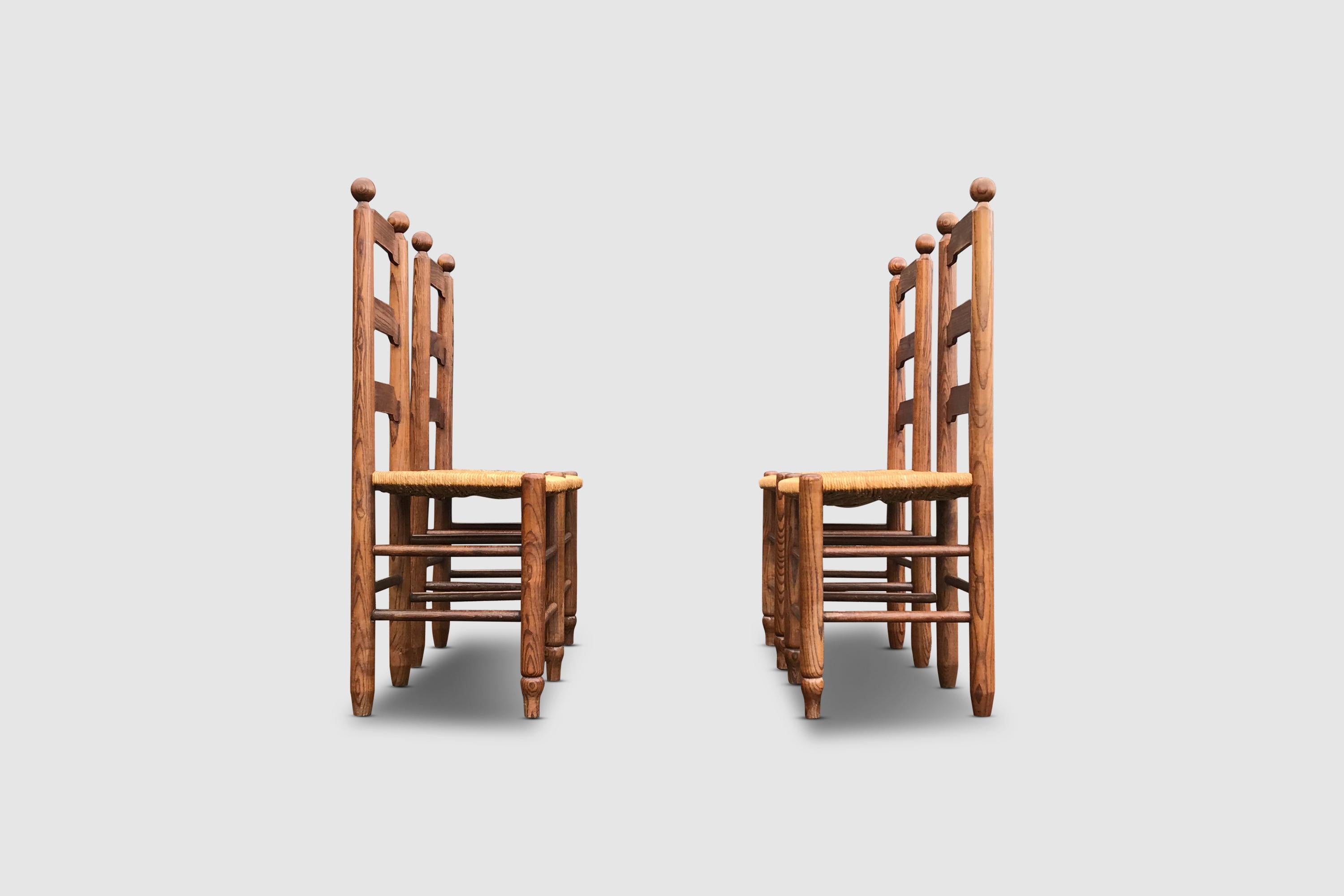 Set of rustic oak and wicker chairs by the French artisan furniture house Georges Robert.

The chairs have the typical carved knot design on top. The backrest is triple slatted and carved in traditional fashion. The chair has thick oak columns that