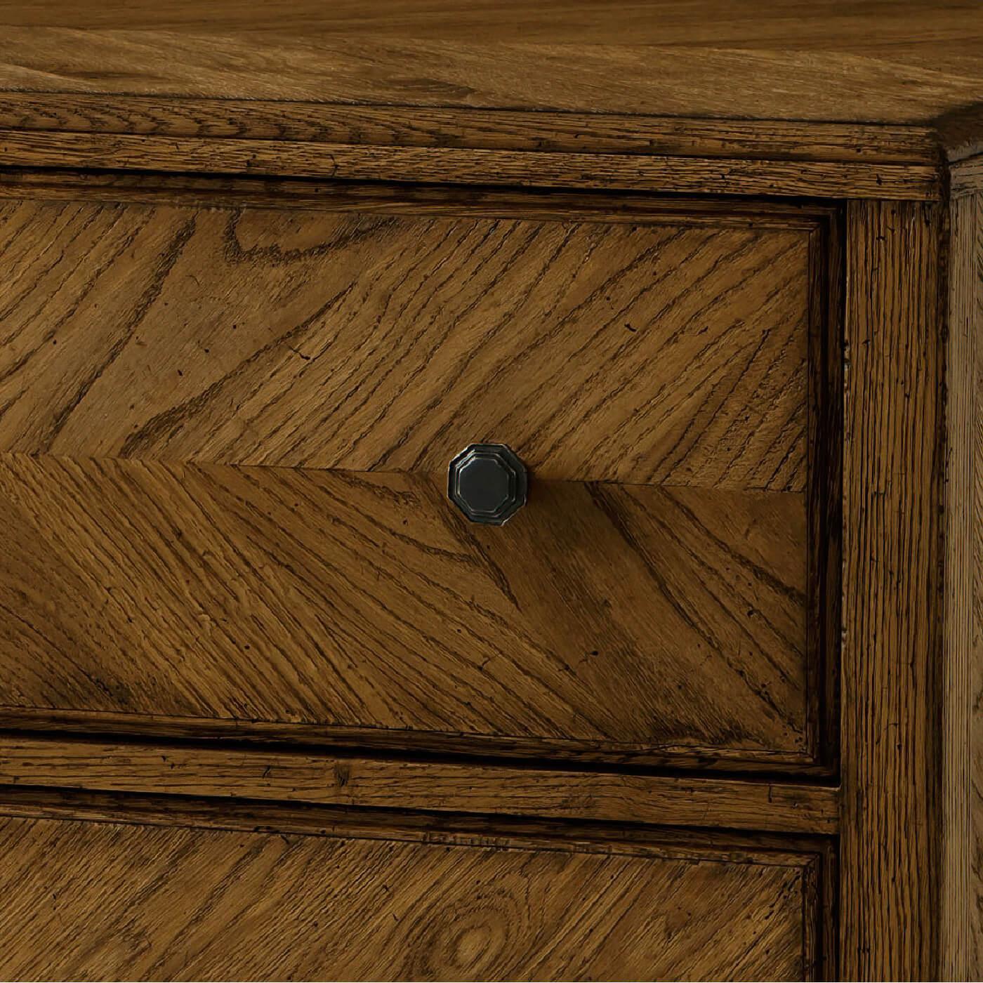 A dark rustic chest of drawers crafted with rustic oak. It has a mirrored herringbone oak parquetry design with three oak-sculptured drawers accented with Verde Bronze finished knobs and beautifully tapered oak legs.

Dimensions: 46