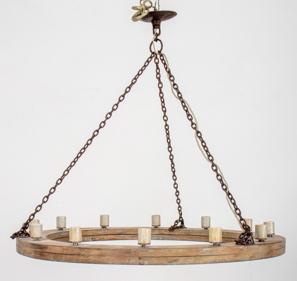 Rustic cerused oak and patinated iron chain twelve-light wheel form chandelier. 

Dimensions: 33
