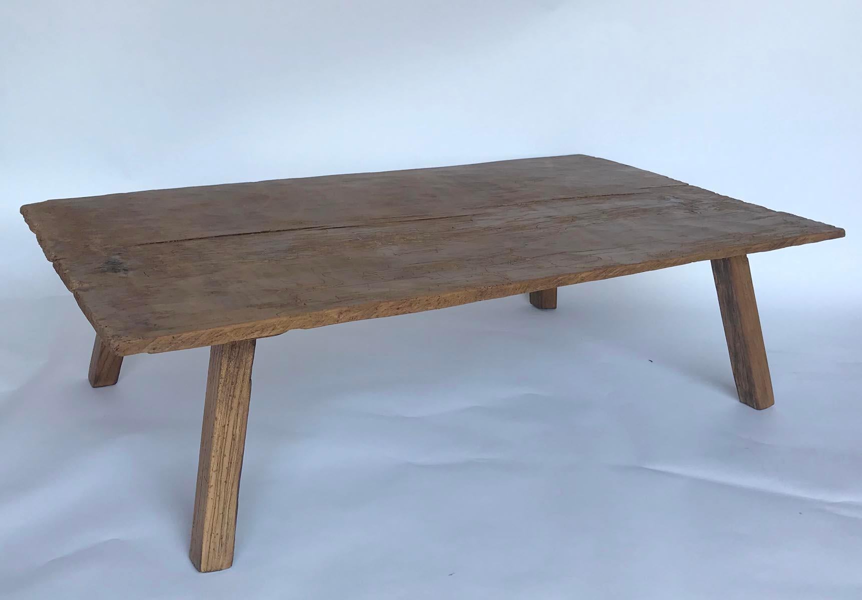 Coffee table made with an antique, very rustic one wide board top from Guatemala. Newer legs have been finished to match the top. Table is hand hewn but flat to place things like glasses and accessories. There are old worm holes in the top showing