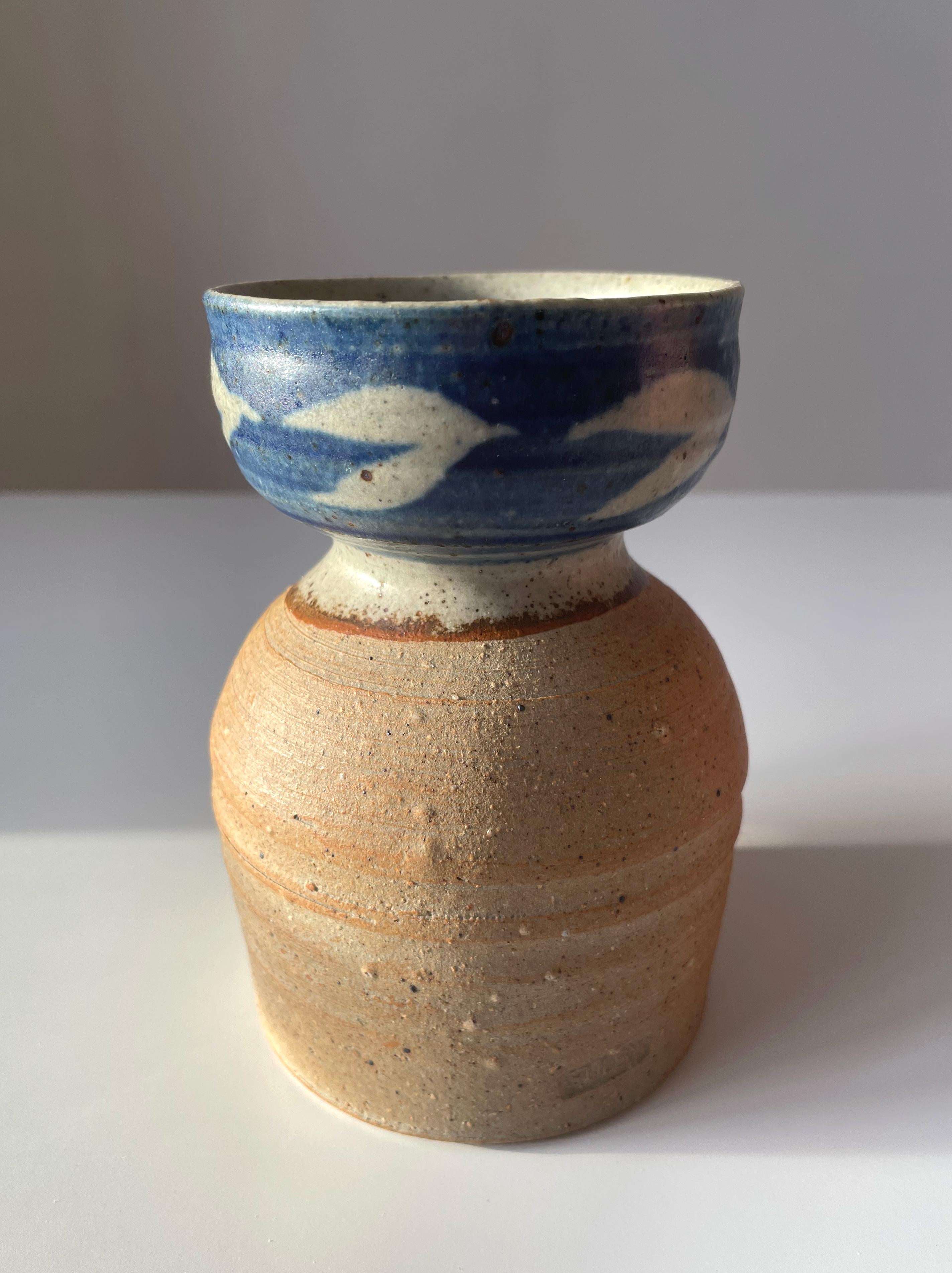 Handmade Danish modern ceramic bottle vase with blue and sand colored organic decor over rustic raw base. Pattern resembing leaves or birds in flight. Sand colored glaze on the inside. Stamped on side. Beautiful vintage condition.