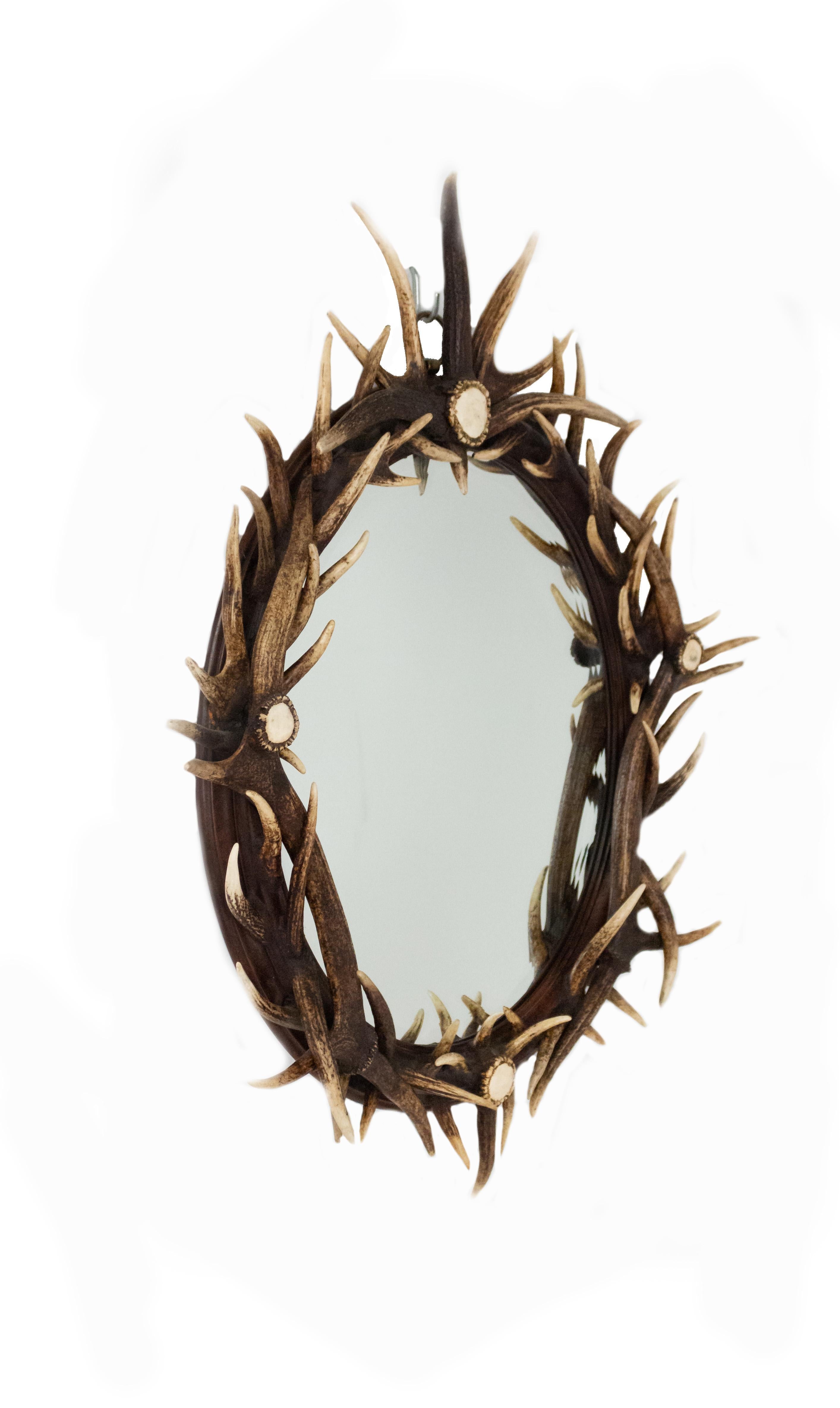 Rustic Continental style (19th-20th century) oval wall mirror with antler-mounted frame.
 