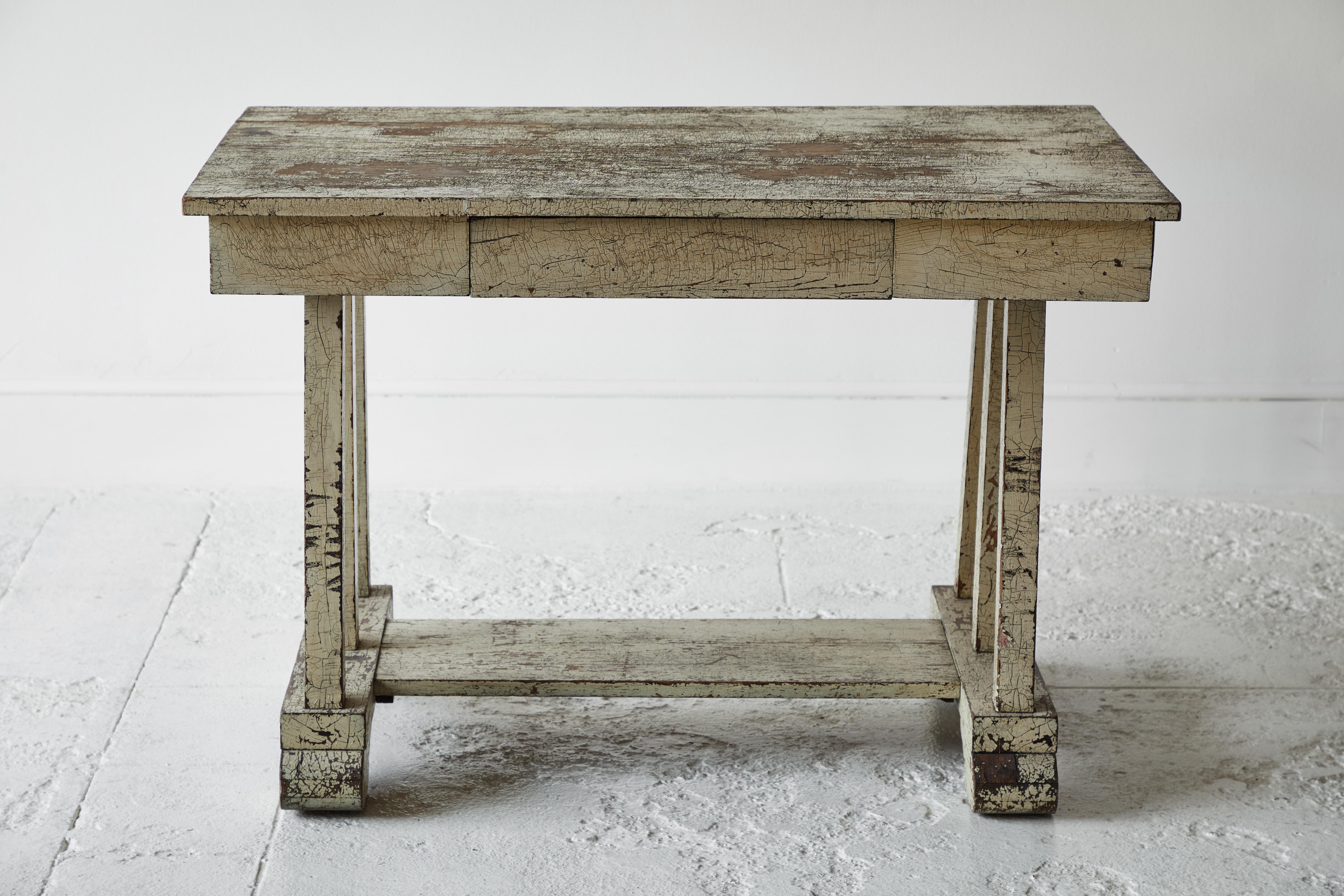 Rustic pale yellow painted desk with a stretcher base. The desk offers a single recessed drawer, original distressed paint adds to the rustic charm.