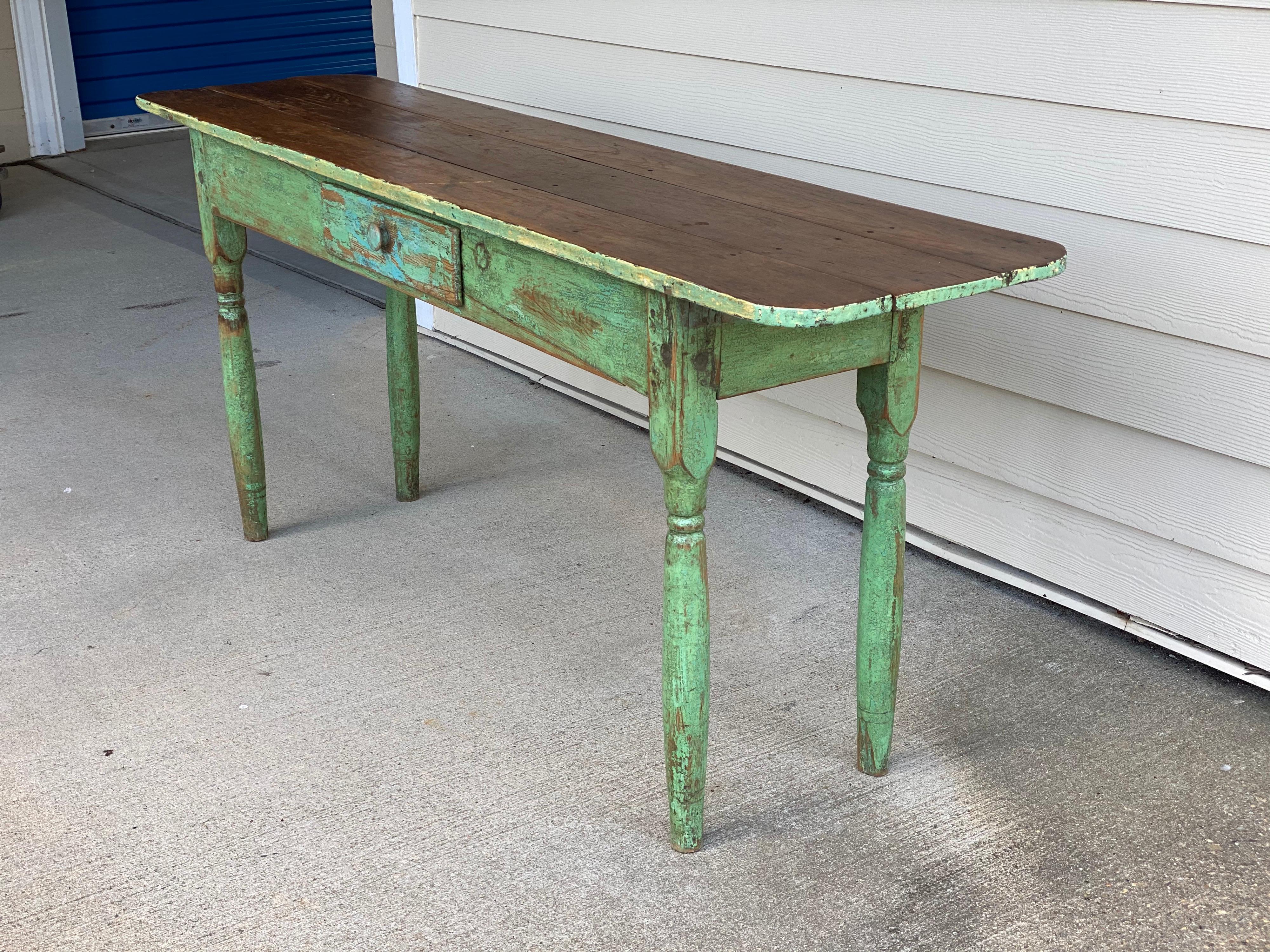 Rustic painted narrow console table
This console has a hand painted base in a green color leaving an exposed wooden top. It also has a single drawer towards the middle. The table itself extends further than the legs, but overall the console is