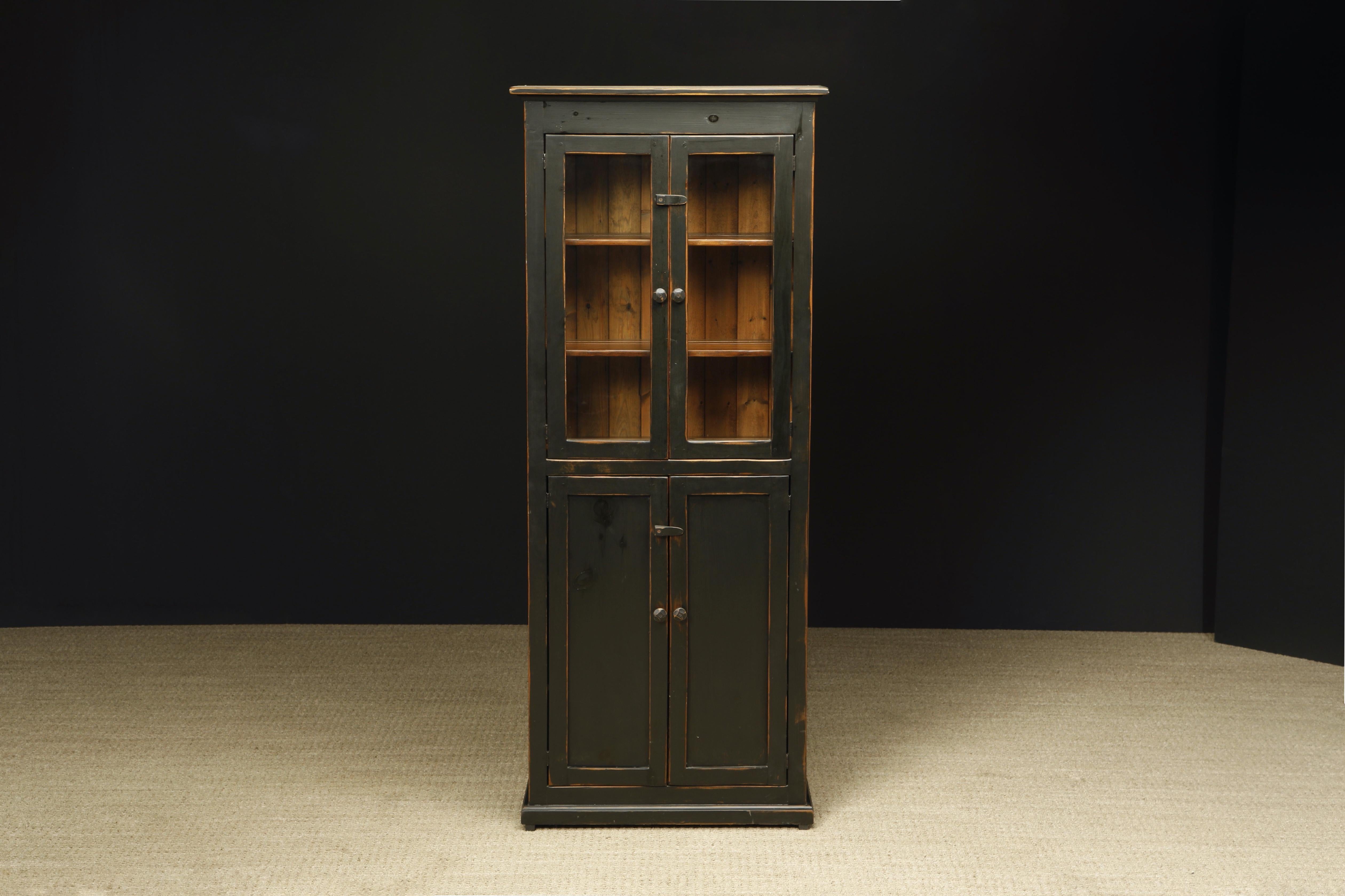 A lovely painted Pine cabinet in a rustic style featuring an intentionally aged look with two glass framed upper cabinet doors opening to two shelves, above two solid wood doors opening to two shelves. 

This beautiful painted pine cupboard
