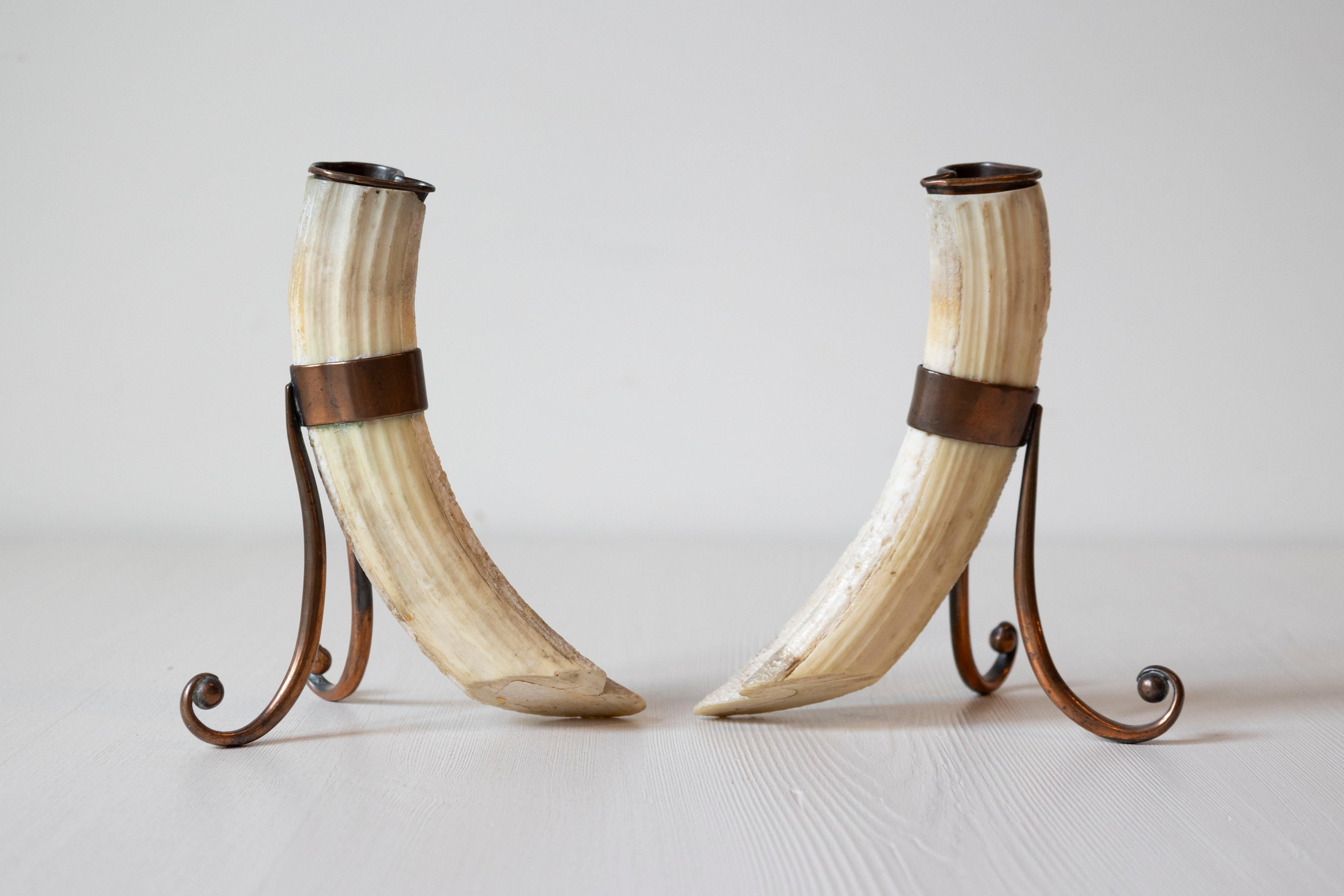 A pair of antique 19th century game animal horns mounted on metal stands. Created during the 19th century, each of this pair of mounted objects features a game animal horn fitted with a removable top. Mounted on metal stands with scrolling feet,