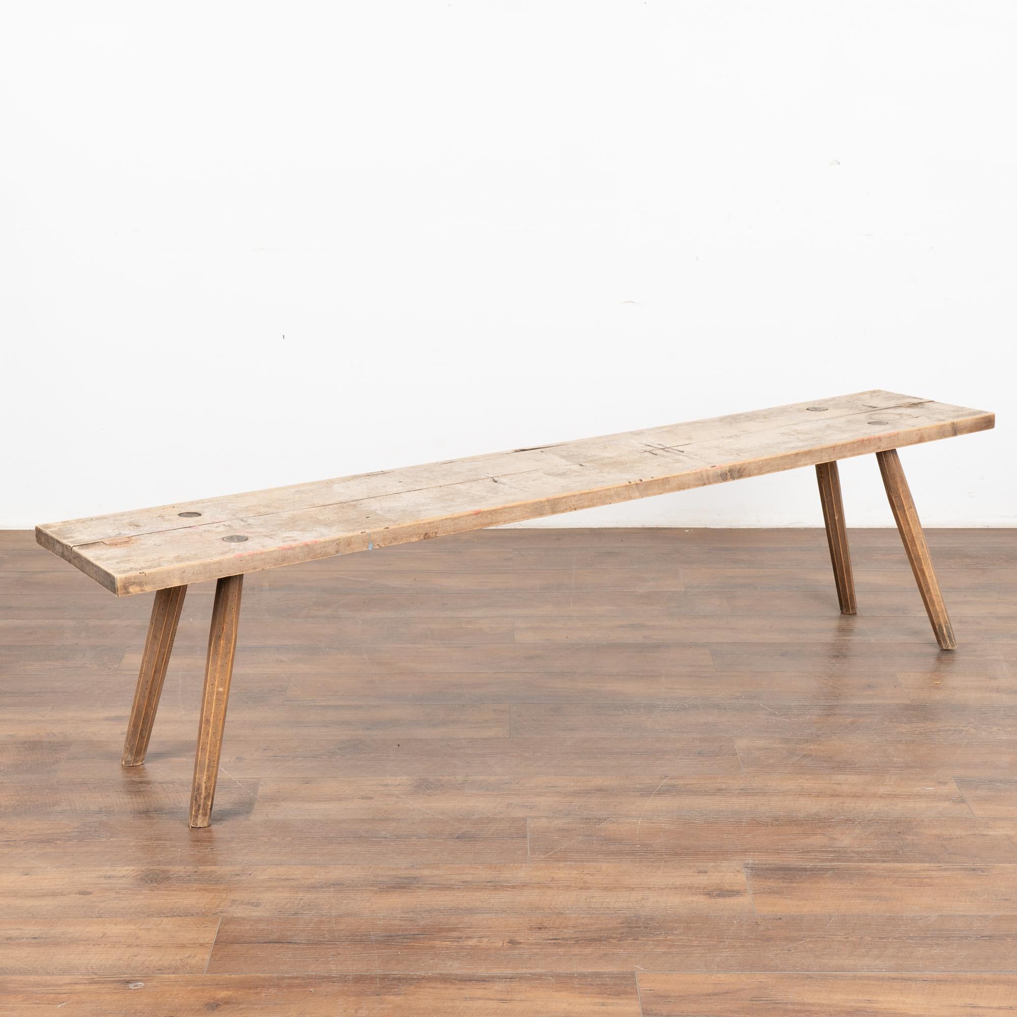 Rustic plank top bench with splay peg legs, just under 6.5' long.
The top reveals generations of use with cracks, nicks, stains and old dried worm holes which add character to the narrow bench.
Restored and waxed, this bench is strong, stable and