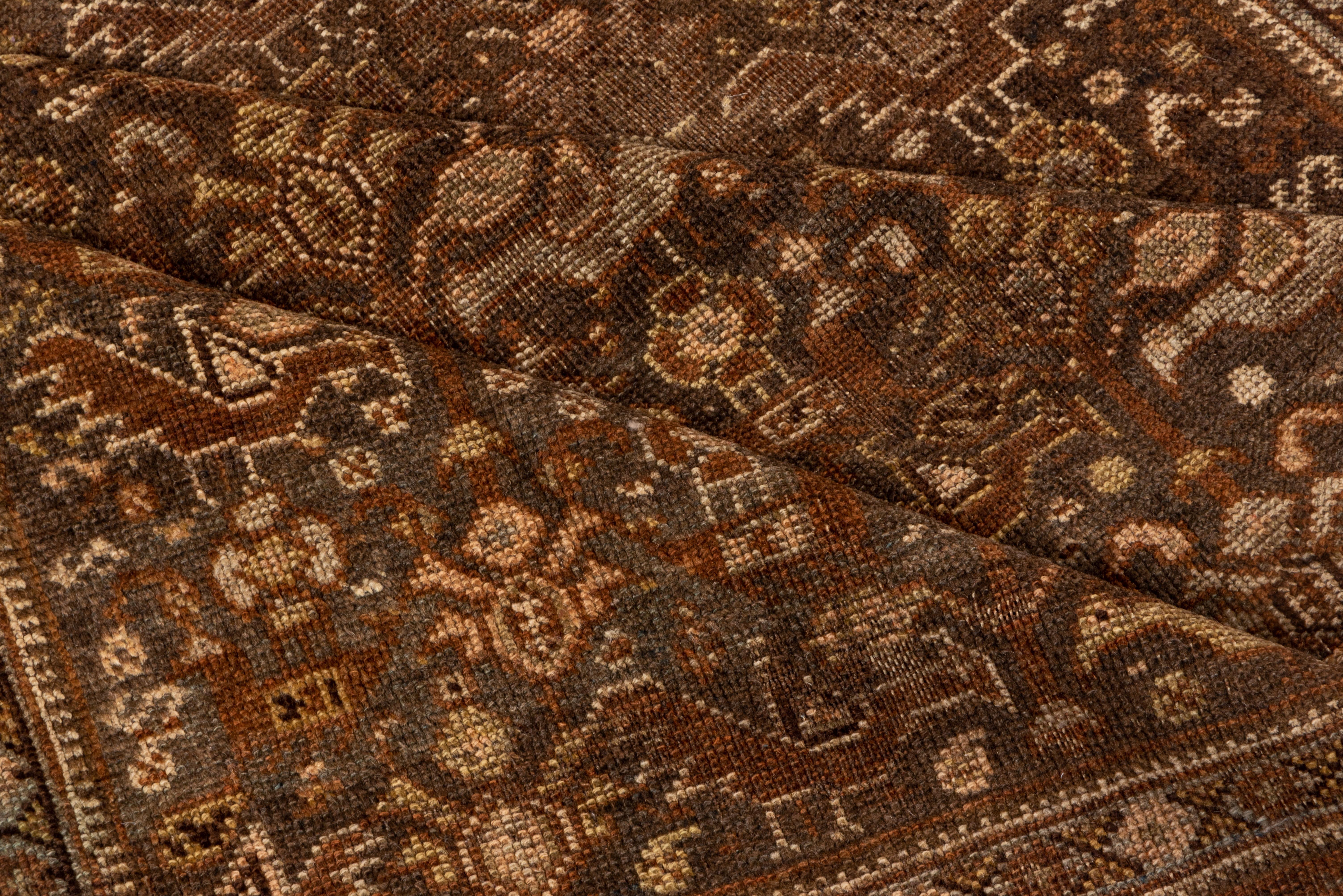 The shiny Dark brown and rust field displays myriad characteristic Southwest Persian chickens and birds, along with stylized flowers and rosettes, The reddish brown border presents squares linked by rosettes, and enclosing reversing botehs. Moderate