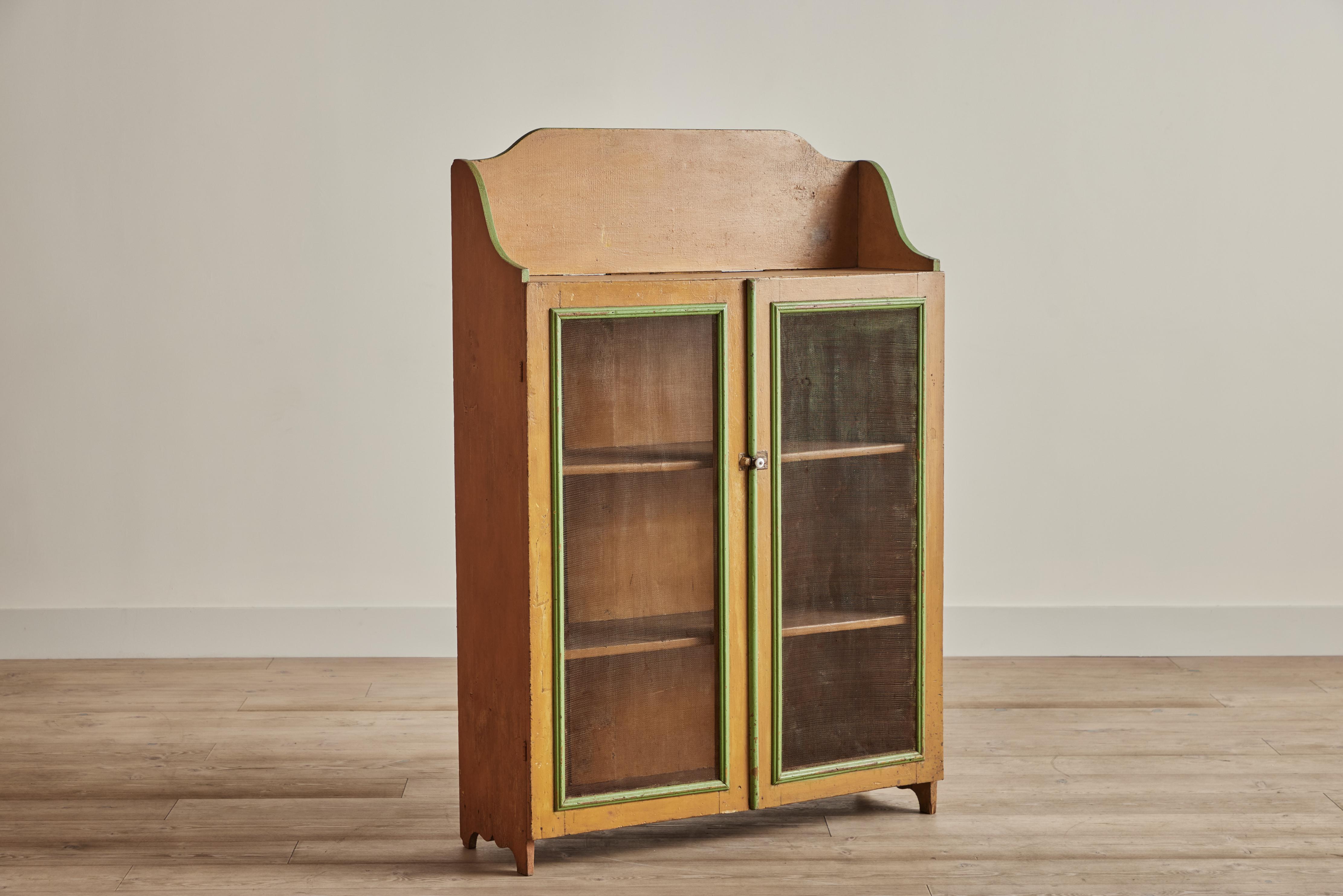 Rustic 19th century gallery top pie safe cabinet painted in a vibrant pumpkin color with bright green trim. Interior compartment as two shelves for ample storage. Visible wear throughout that is consistent with age and use. 