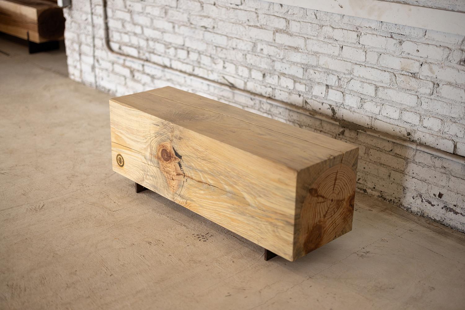 Notre banc à poutres utilise des rondins de pin local récupérés pour créer un banc rustique pour l'intérieur ou l'extérieur. Étroites et sans dossier, les lignes simples expriment la texture naturelle du grain final de chaque espèce. La poutre de