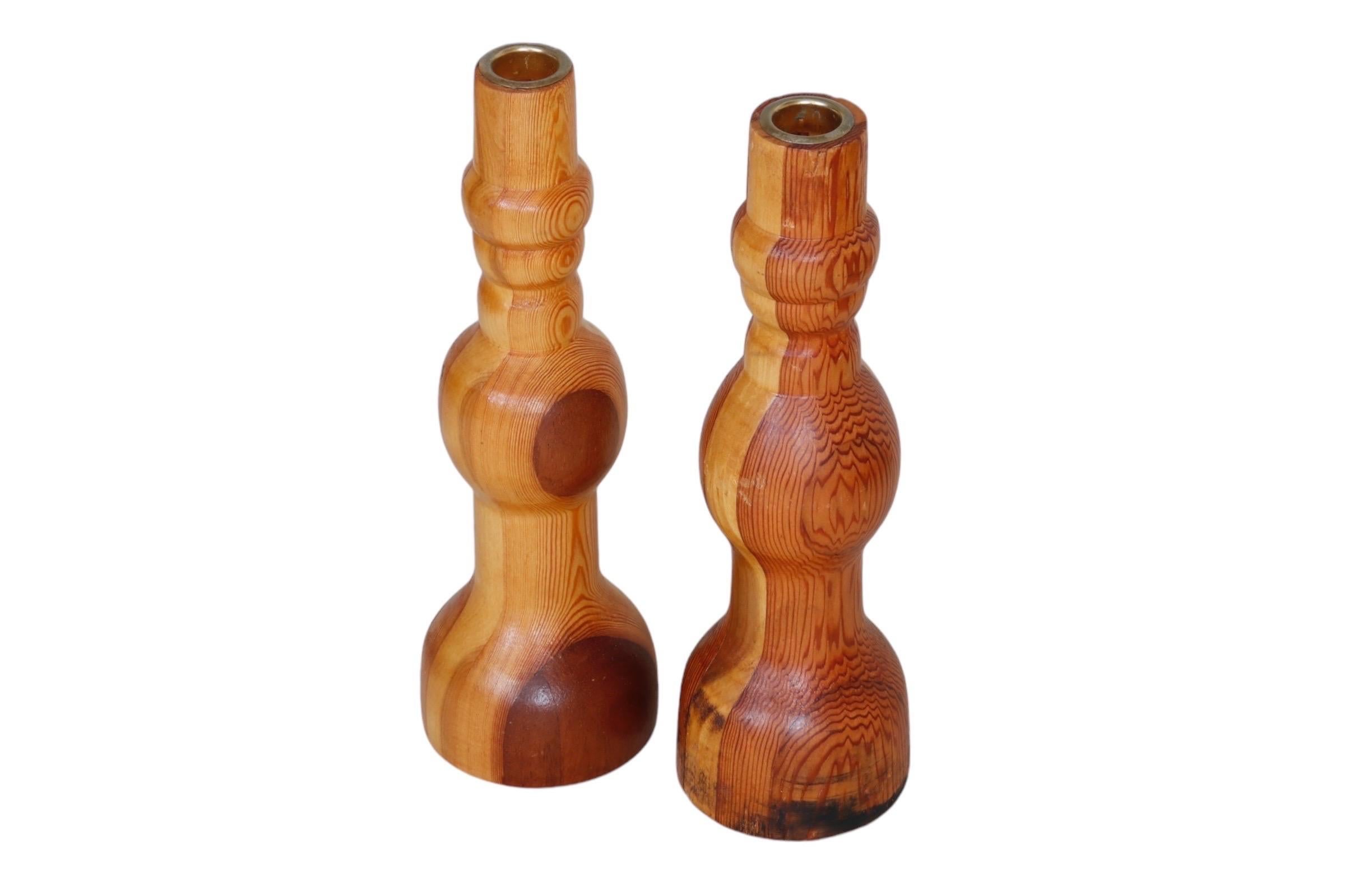 Una coppia di portacandele rustici torniti in pino. Con una splendida venatura, le semplici curve mostrano le macchie e le strisce del legno. I piani sono incastonati con capitelli in ottone. Dimensioni per portacandele.