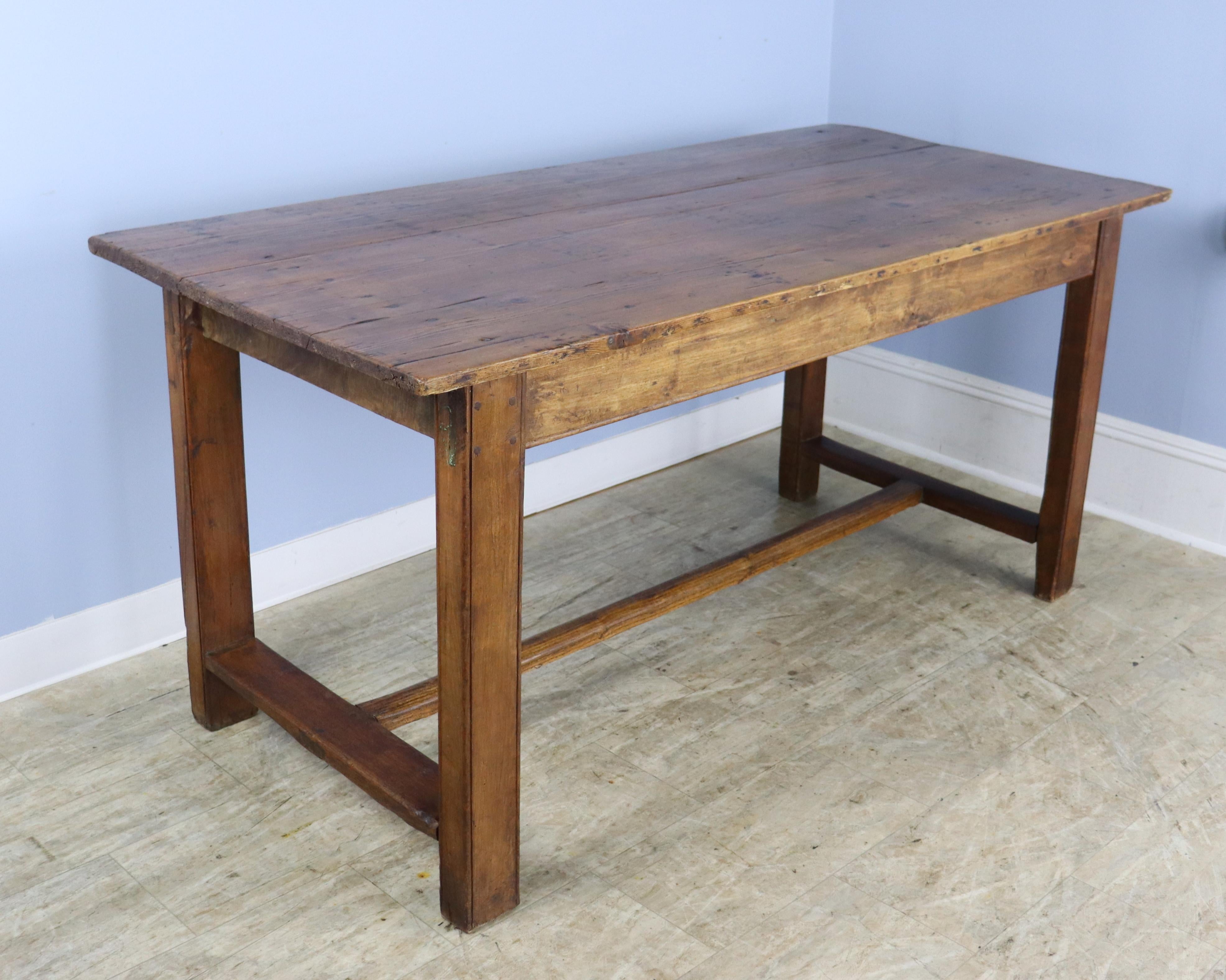 A smaller rustic trestle based farm table with a pine top and an oak base.  The top has been polished to a shine and has lots of good pine grain and texture, as well a some age appropriate marks and wear.  The bottom has lovely chunky legs and the