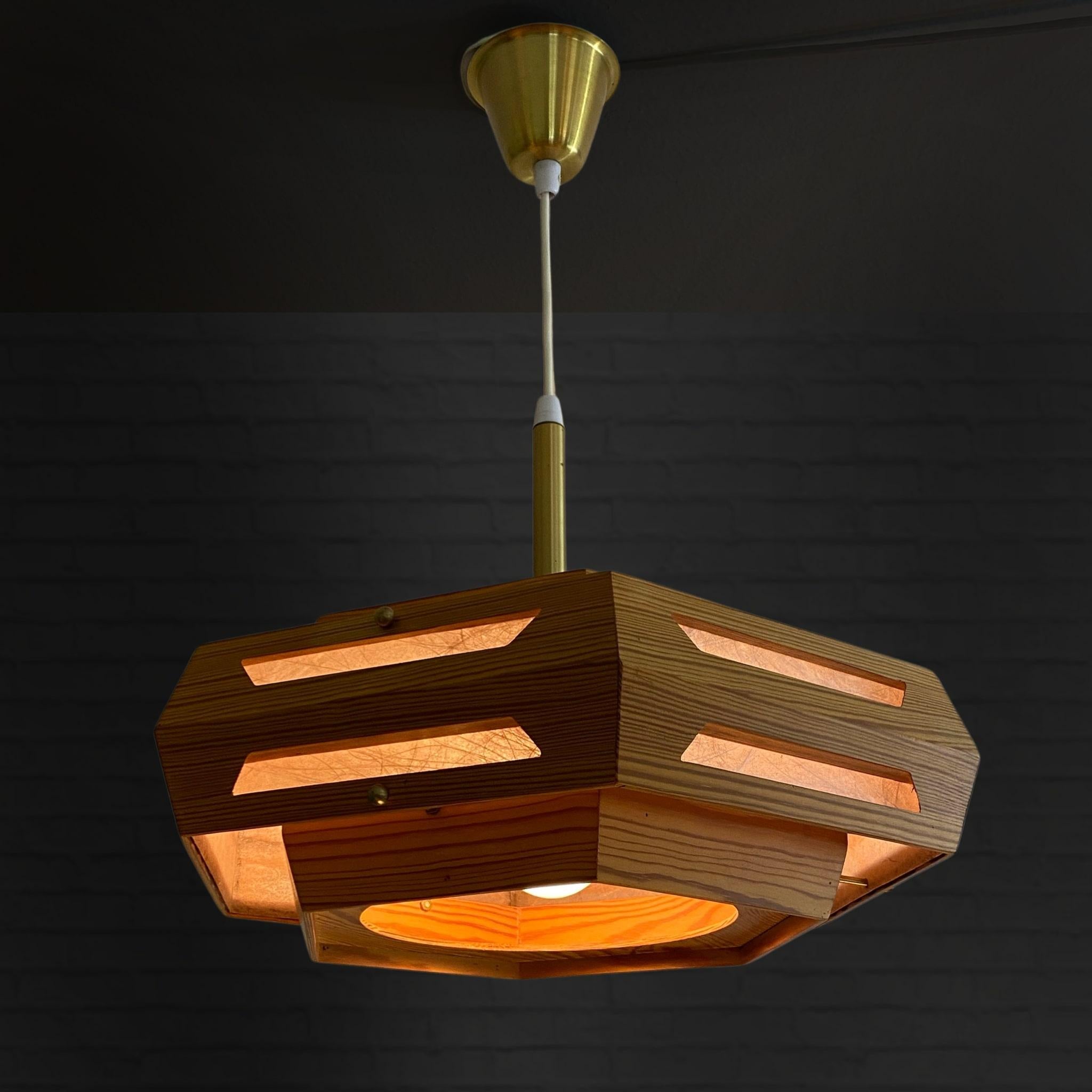 Swedish 1970s rustic pendant lamp made from solid pinewood with brass fittings. Thin glass fiber sheets act as reflectors, giving a soft and pleasant light without glare. Complete with a matching brass canopy at the ceiling. In the manner of