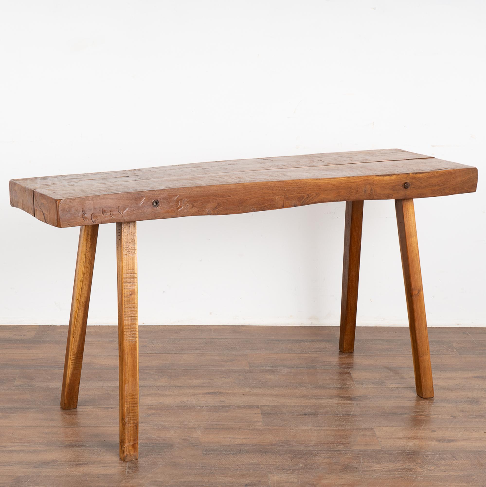This rustic plank top console table with splay peg legs originally served as a work table.
The over 3