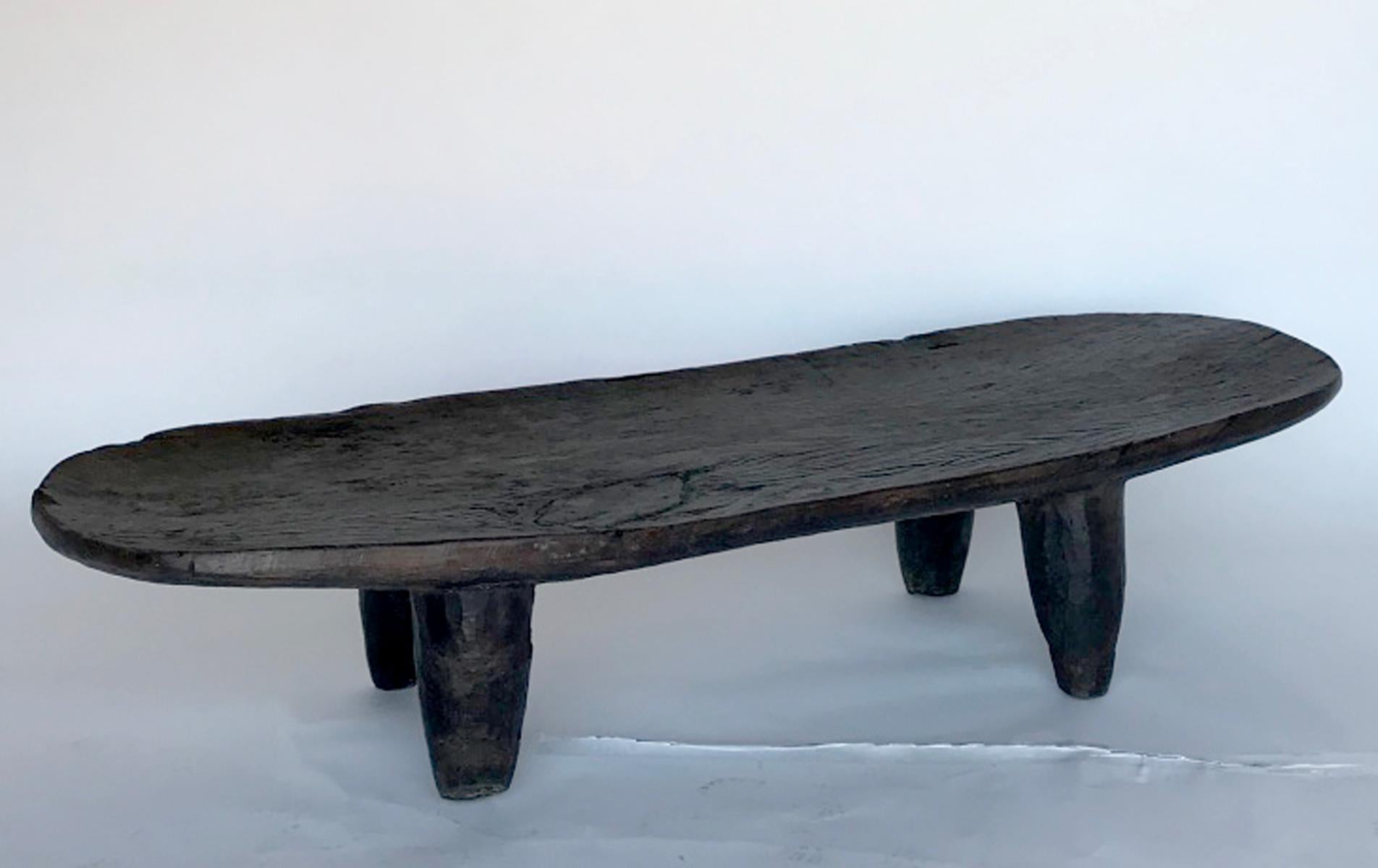 This ld bed is carved out of one piece of wood and features an oval top and conical legs. The color is a very dark brown. It has some old repairs on leg and on the top. From the Super tribe in Northern Nigeria. Completely sturdy and functional.