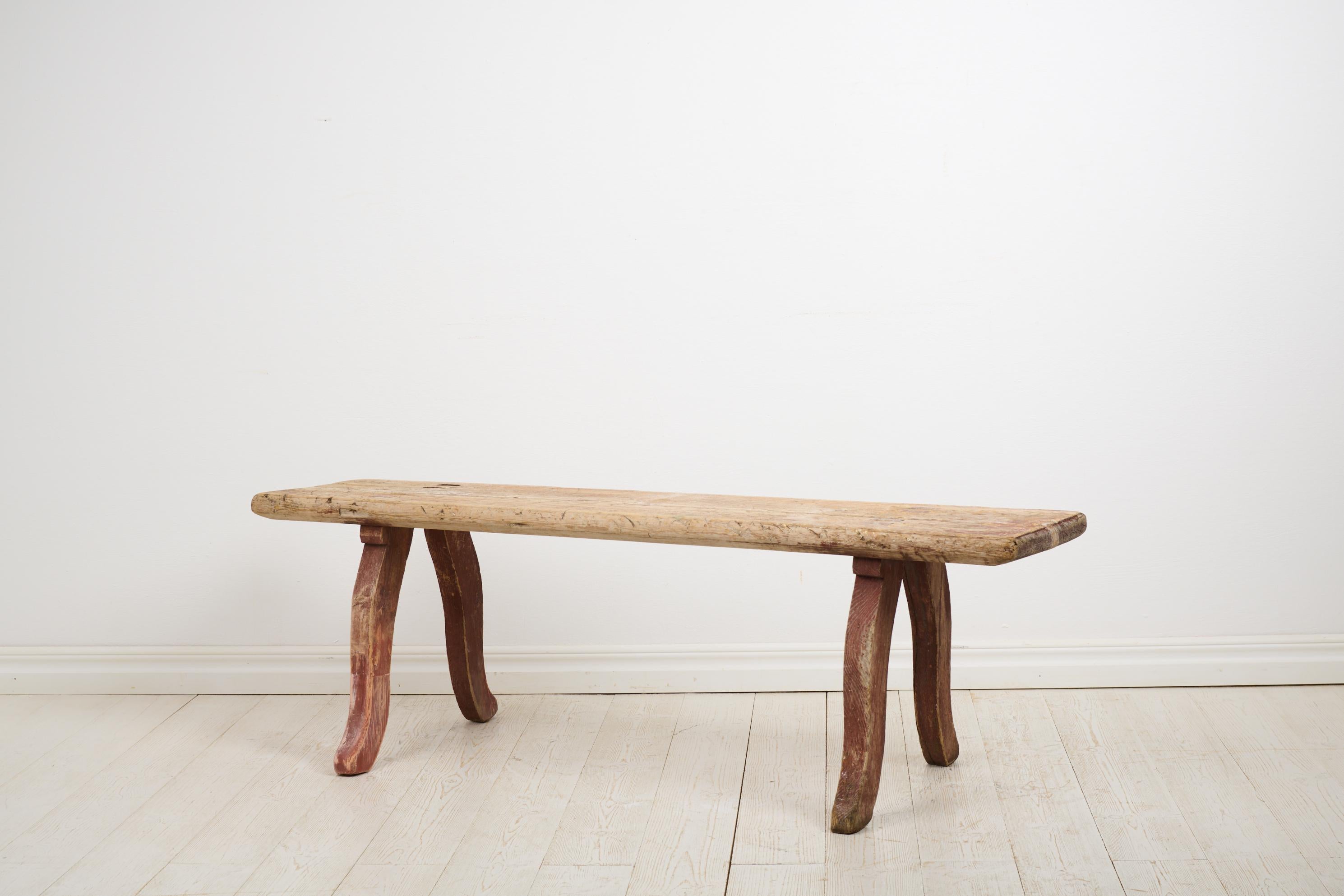 Rustic primitive antique bench in folk art from Northern Sweden. The bench is made by hand in solid pine and made around 1820. A primitive, rustic and genuine bench with a seat made from a single board. Curved legs in rococo style. Original