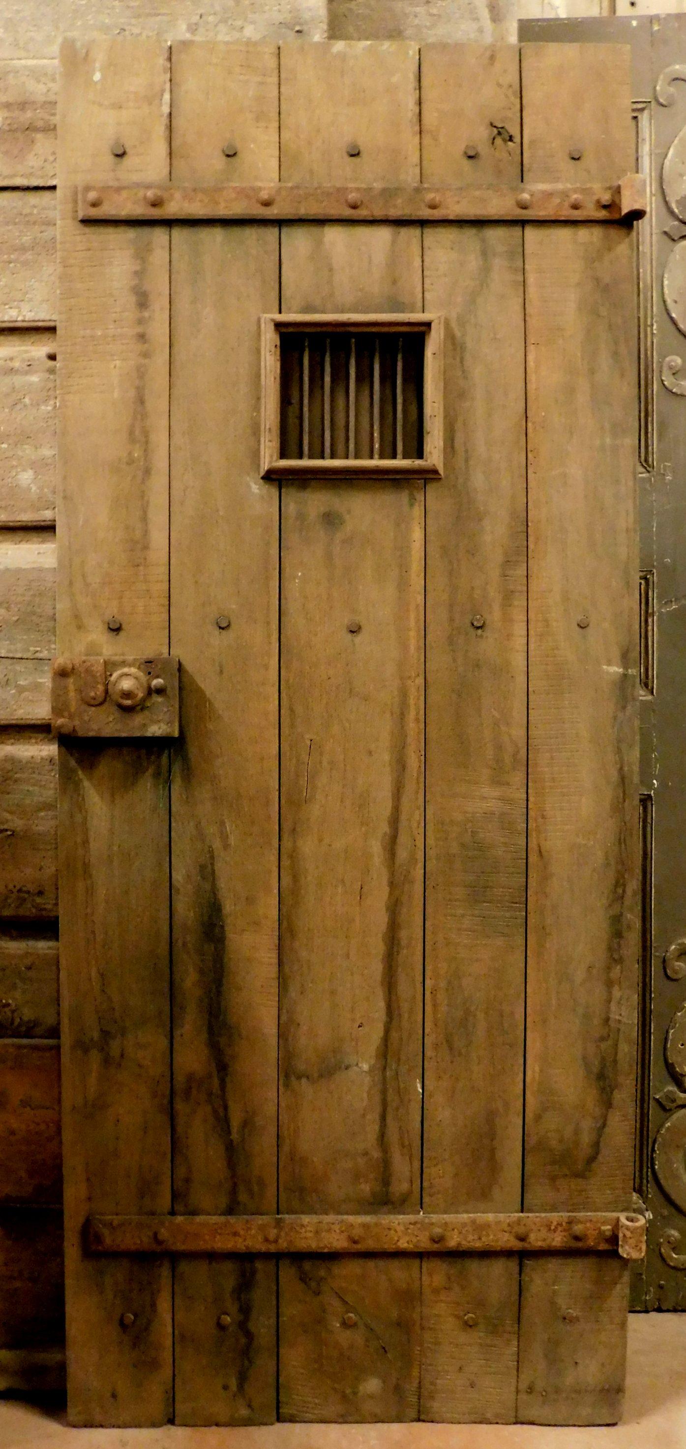 Antique rustic prison door, studded boards with original window and locking irons, solid chestnut wood door, 19th century, built for an old noble rustic in Italy.
Ideal as a door for cellars, wine cellars, historic commercial premises or for rustic