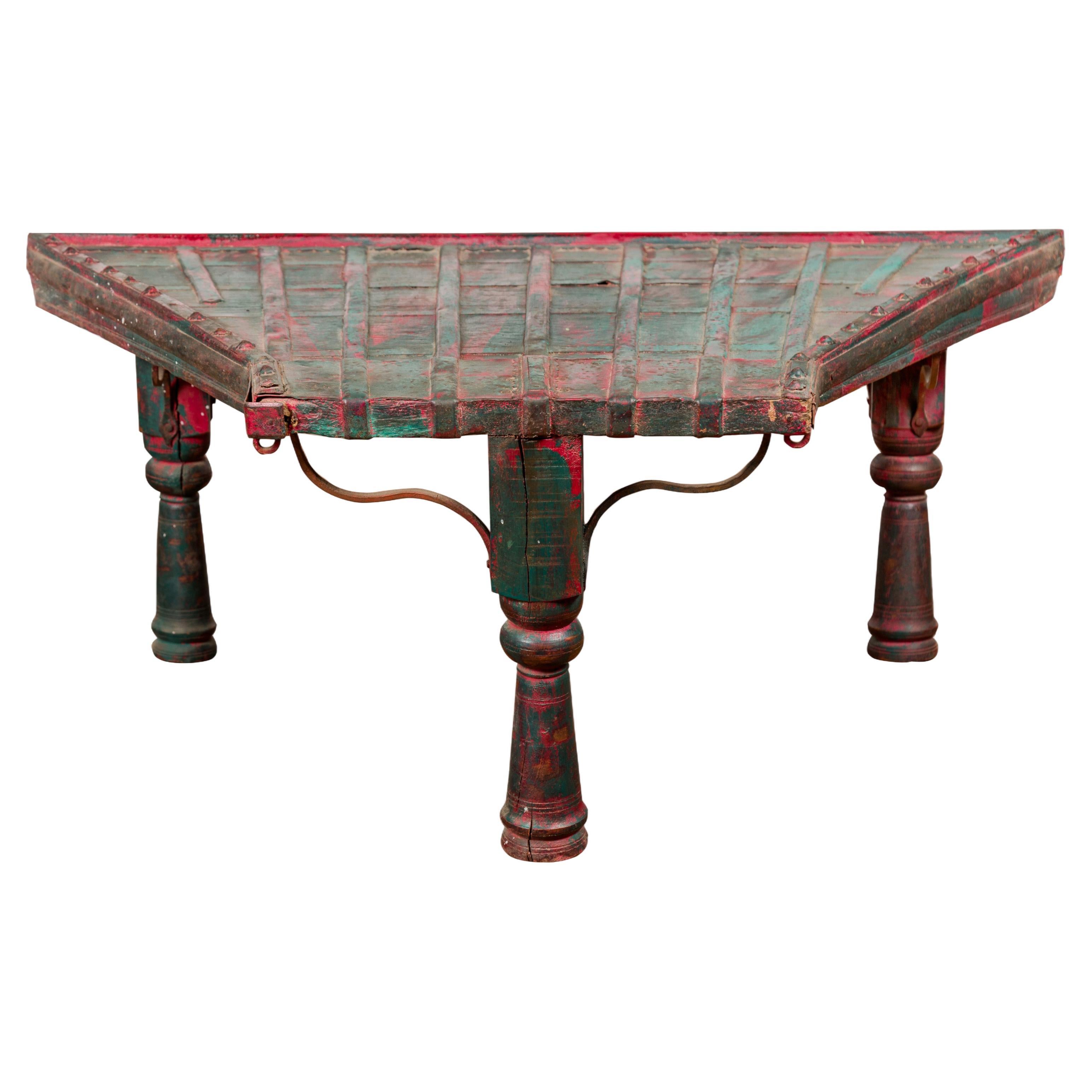 Table basse rustique rouge et verte avec plateau trapézoïdal et traversins en fer