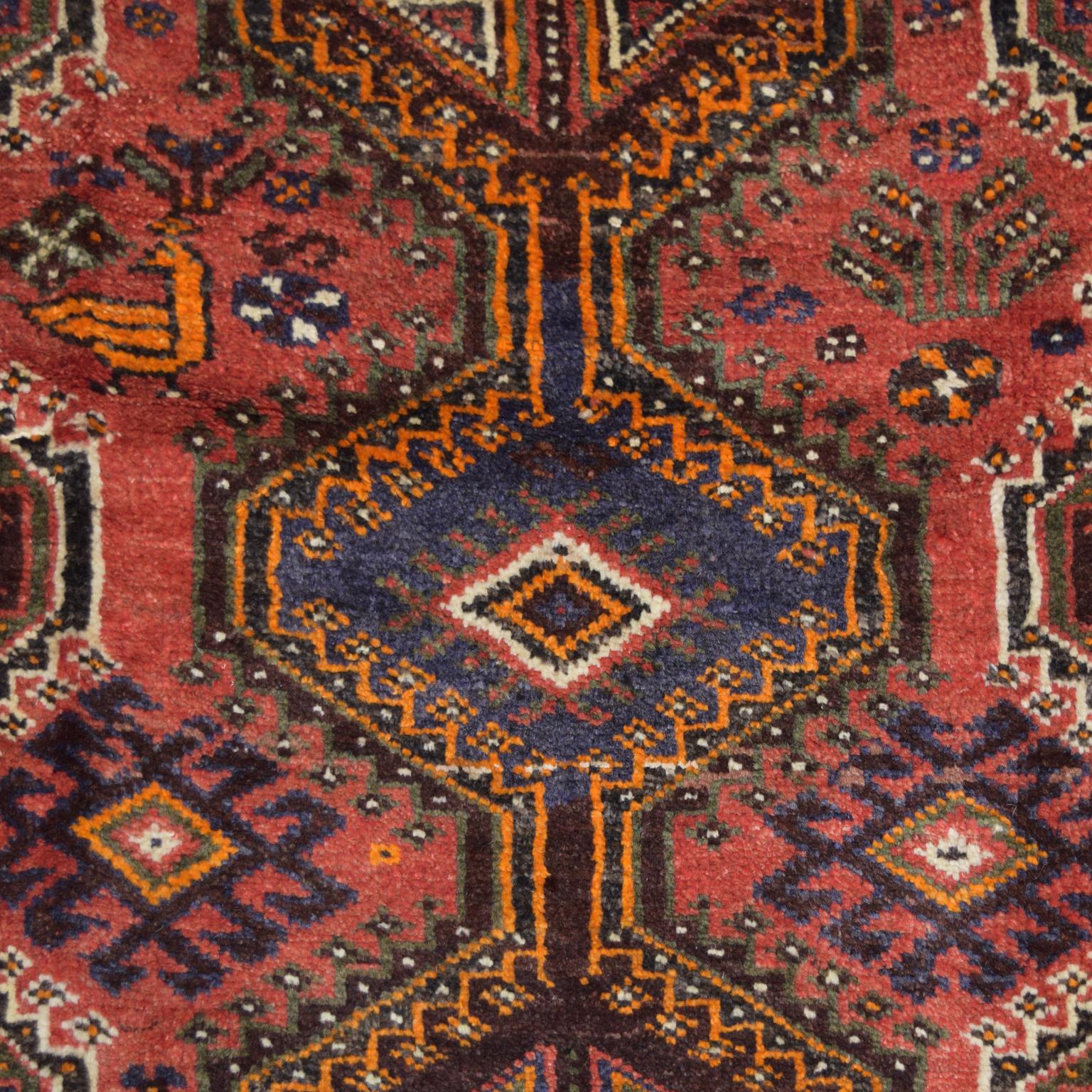 Hand-knotted and organically dyed, this Persian Qashqai carpet in red, pink, and cream wool measures 5’4” x 8’6” and belongs to the Orley Shabahang World Market Collection. Crafted in Iran, this carpet uses a traditional Persian weaving technique.