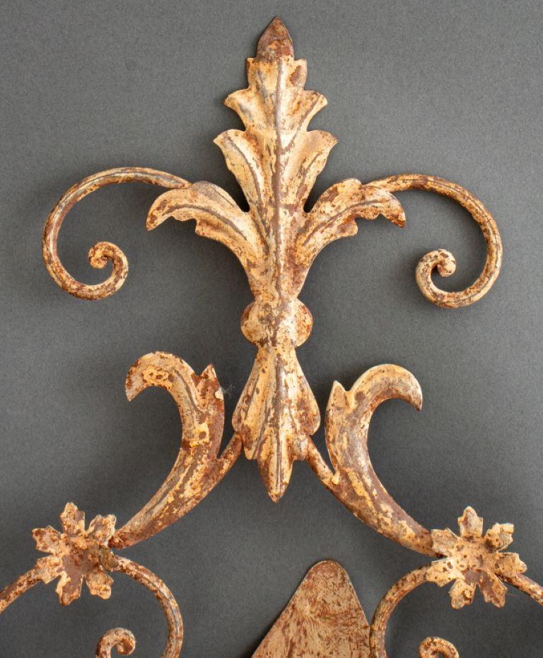 Rustic Rococo three-light tole peinte sconces, each with rococo style metal appliques painted in a a rustic milkpaint, the scrolling cage-form metal backs issuing three scroll arms with candle mounts. Size is for each.
