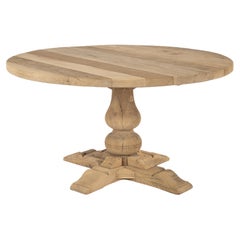 Table ronde rustique en chêne massif récupéré et patiné sur une colonne centrale.