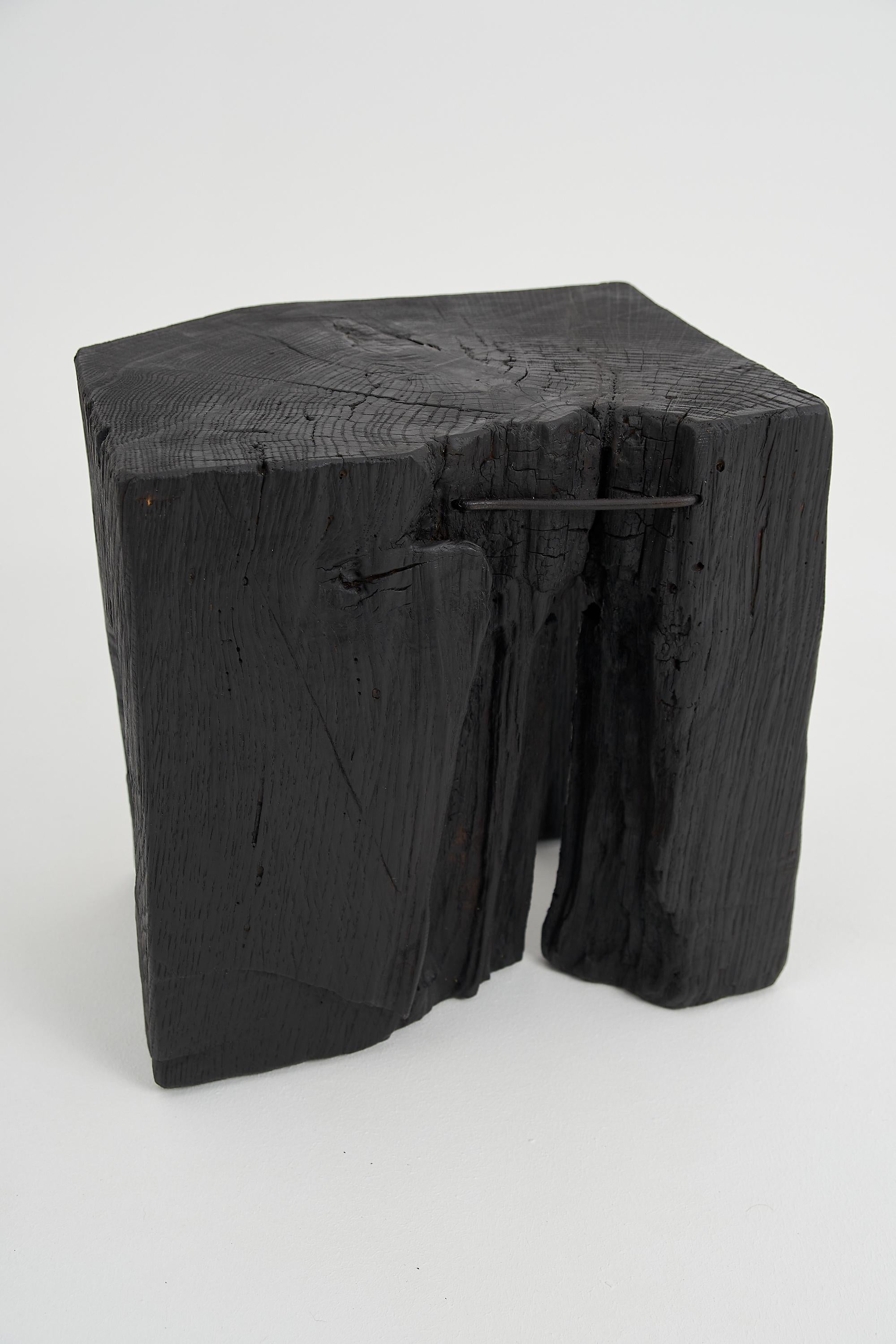 Mesa/taburete auxiliar tallado con motosierra. Tallada en una sola pieza de madera de roble quemada y protegida con aceites de la máxima calidad, lo que garantiza su durabilidad durante generaciones. Este diseño único hecho a mano realzará su