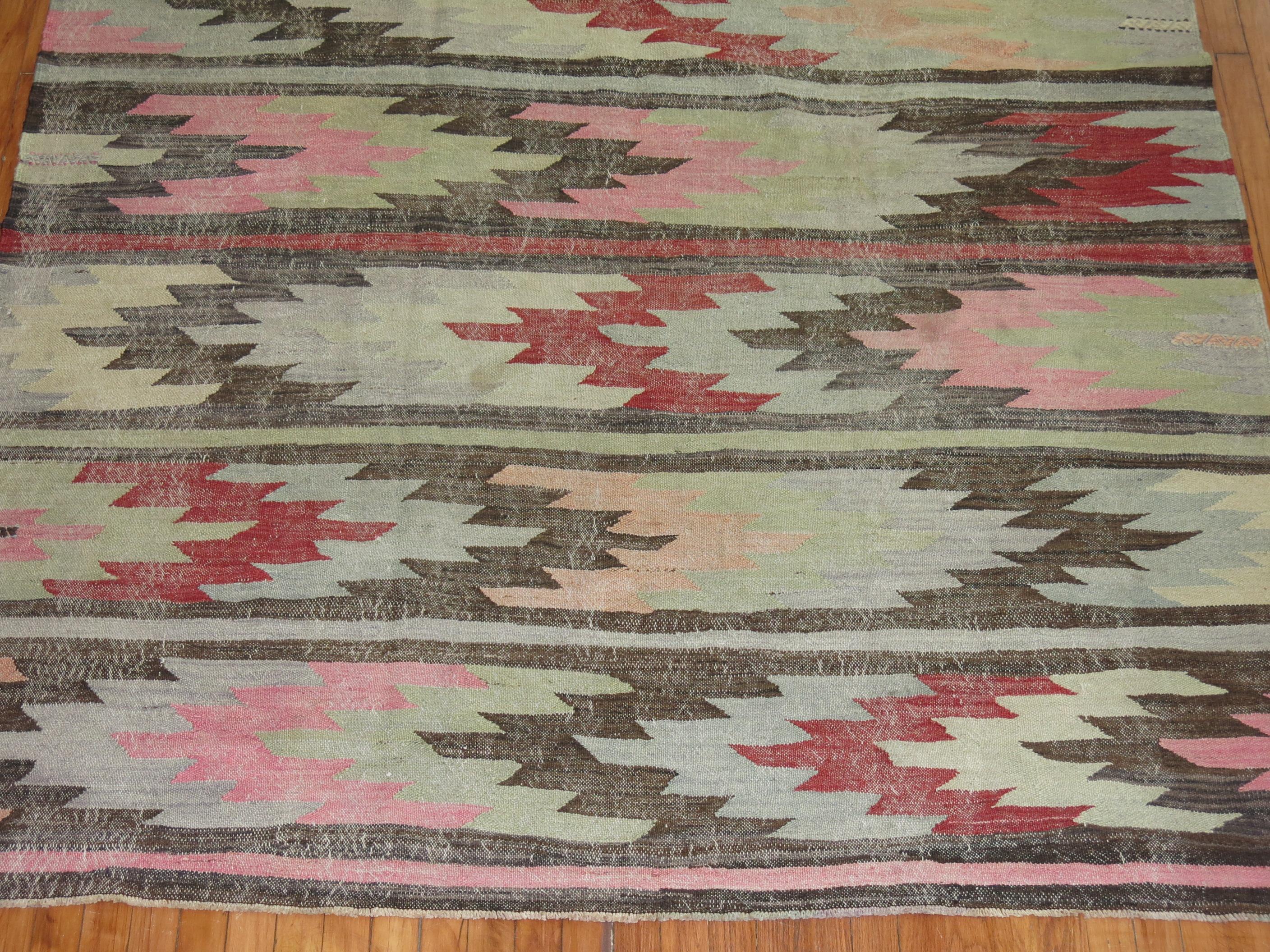 Mid-20th century evenly worn Turkish kilim in pink, green, cream, red, blue and gray accents on a charcoal field.

Measures: 6'1