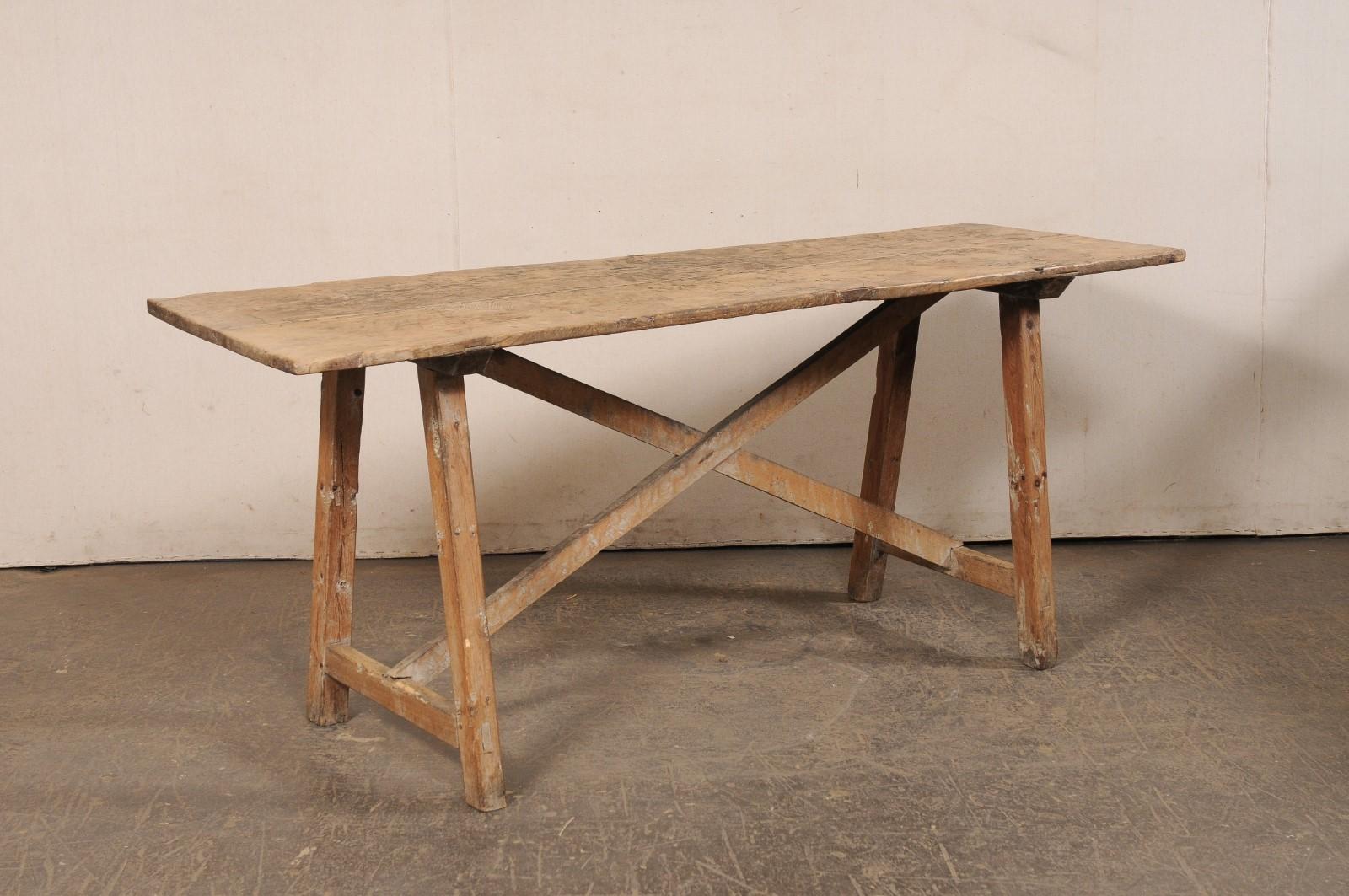 A Spanish wooden trestle-leg table with x-stretcher from the 19th century. This antique table from Spain is rustic and casual with it's beautifully aged wood top, and clean design lines. The rectangular-shaped top is supported with a pair of trestle