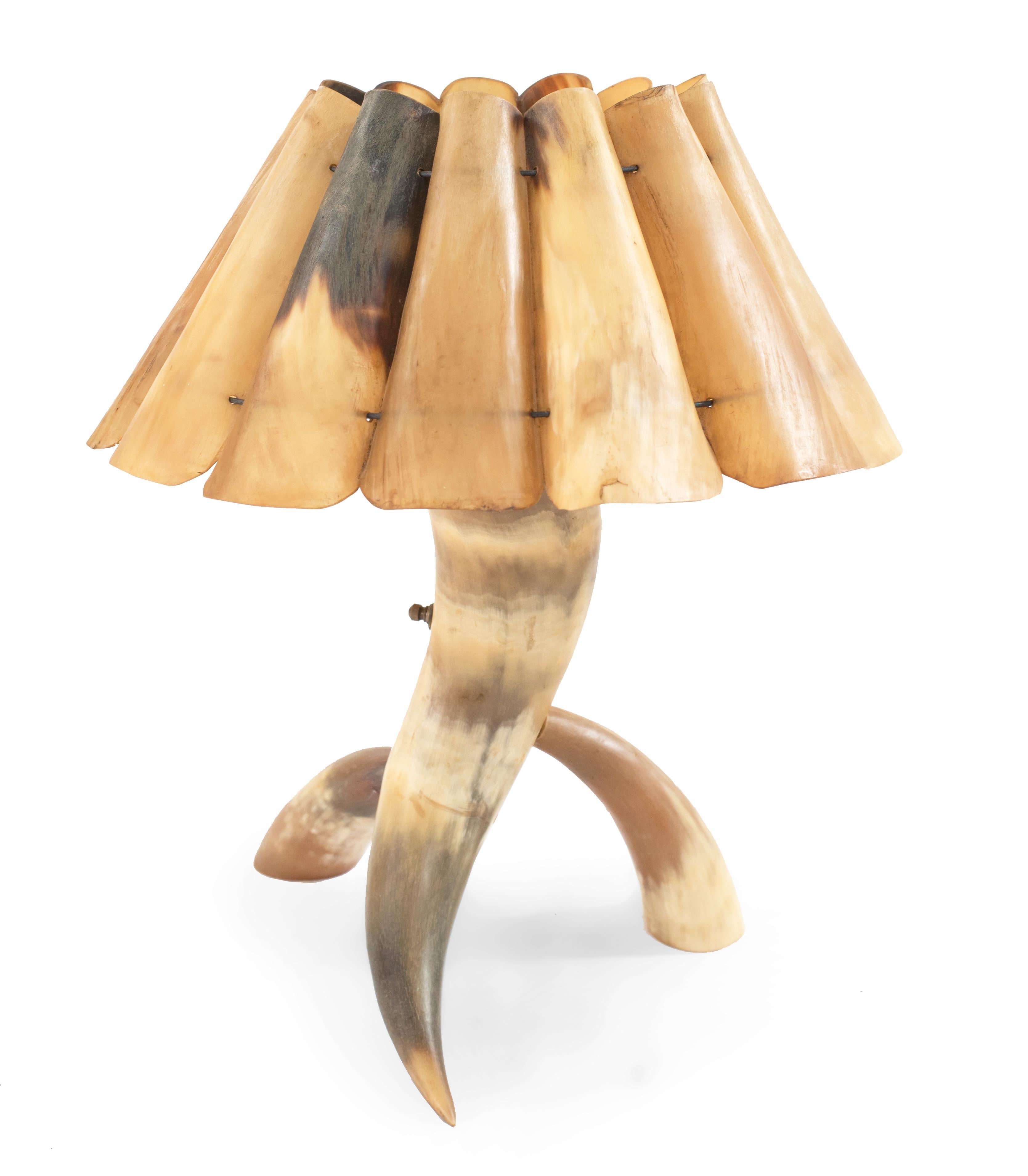 Rustic small steer horn table lamp with a base made of three horns and a shade made of halved and trimmed horns.