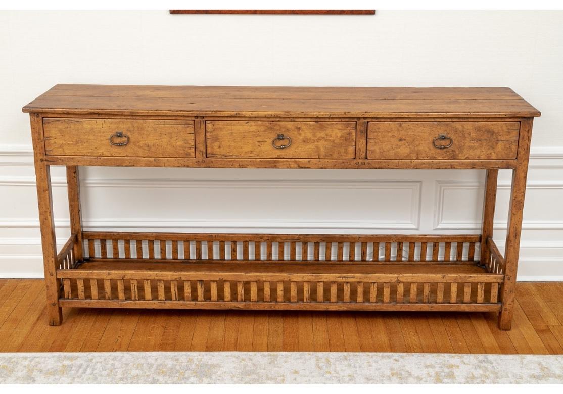 A particularly well crafted Console/ Server in the manner of and possibly by Bausman. Sideboard featuring three frieze drawers with interesting oval iron pulls with square legs and wood gallery on lower shelf with a medium intentionally distressed