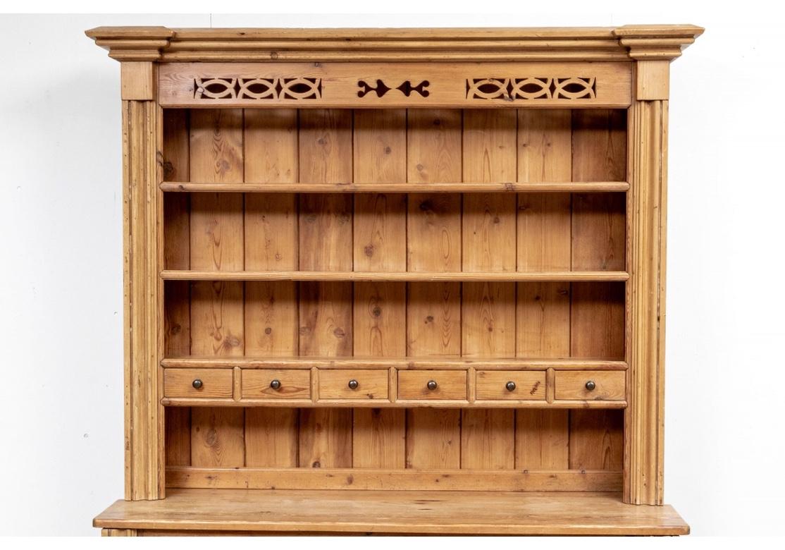 Well-made pine kitchen dresser with a carved top openwork frieze over three shelves with slots for plates. The center with six small drawers. The lower cabinet with four short drawers over two sets of carved double doors opening to a single shelf.